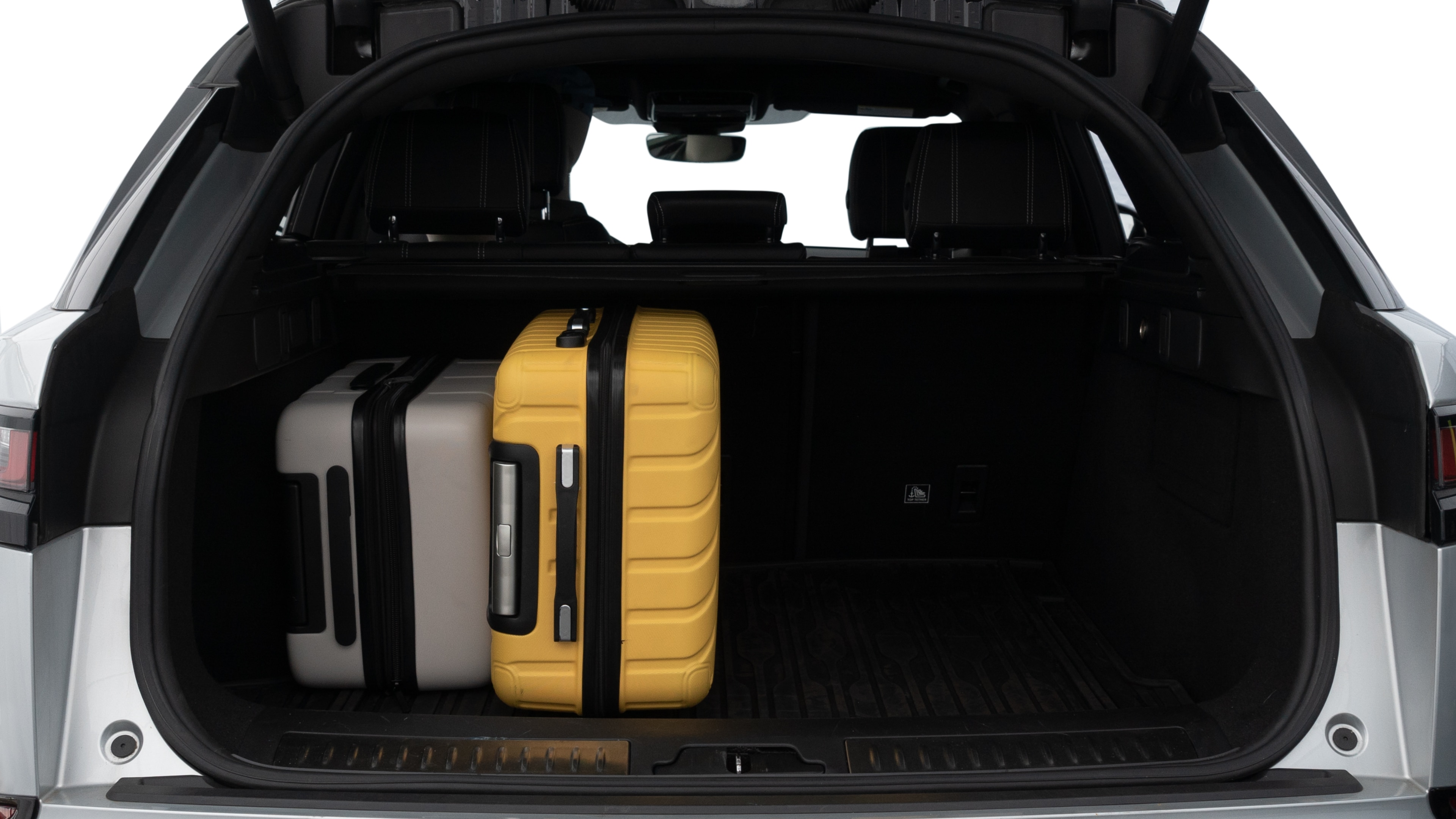 The trunk lid is open, showing full view of the trunk space. Two medium and two small suitcases are placed inside.