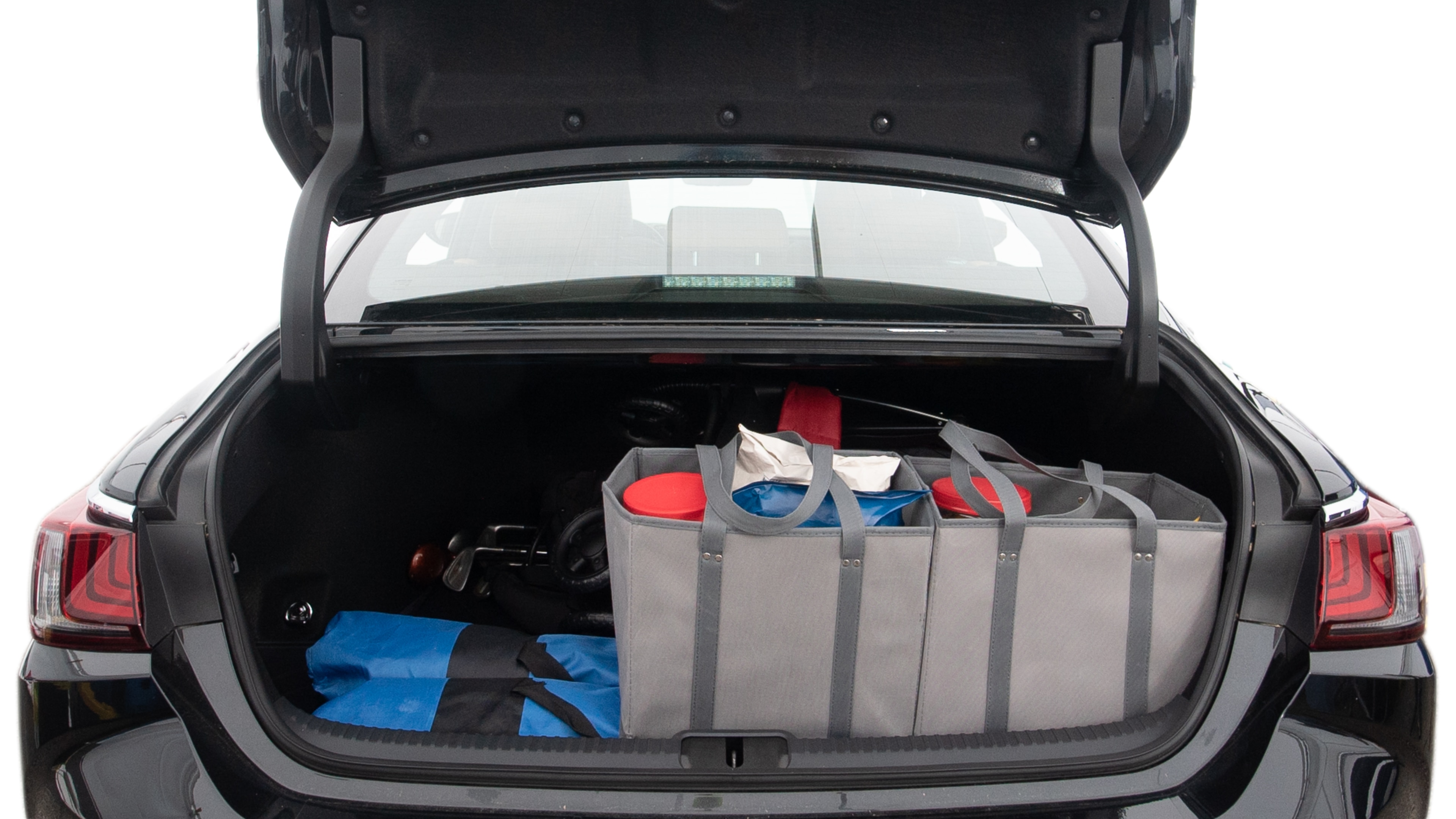 The trunk lid is open showing full view of the trunk. A baby stroller, three grocery carriers, two camping chairs in the carrying bag, and a set of golf clubs are placed inside.