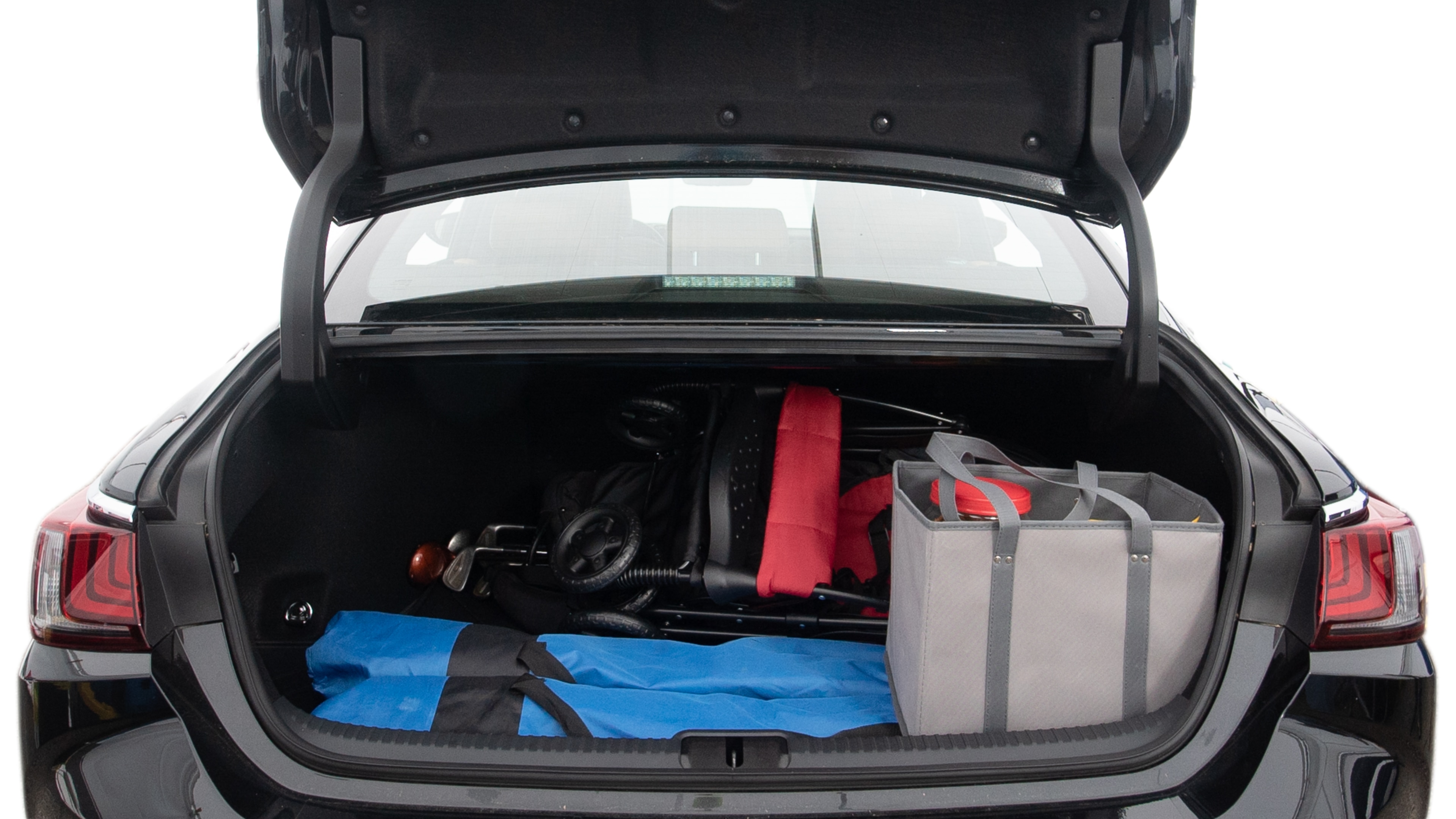 The trunk lid is open showing full view of the trunk. A baby stroller, three grocery carriers, two camping chairs in the carrying bag, and a set of golf clubs are placed inside.