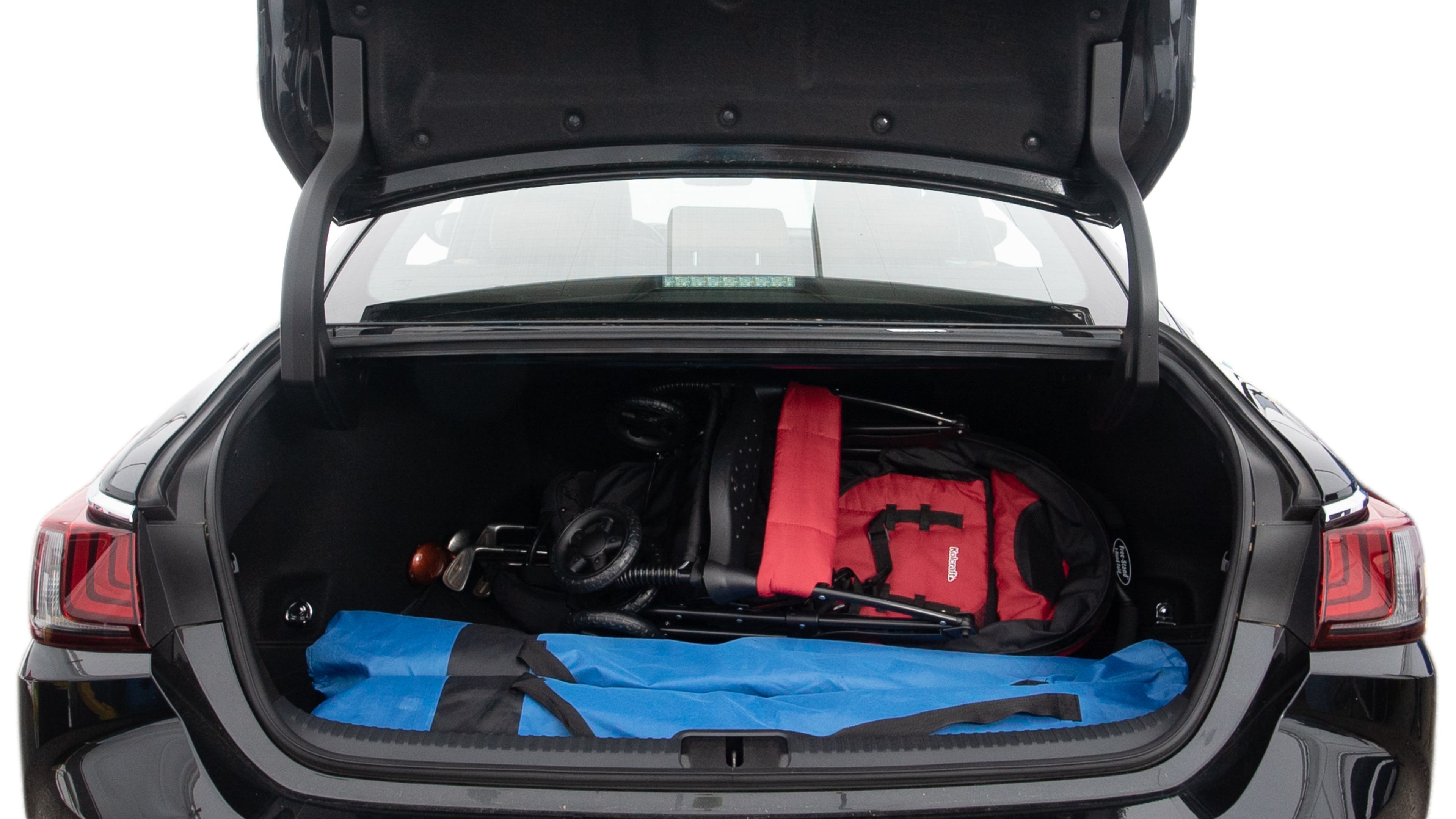 The trunk lid is open showing full view of the trunk. A baby stroller, three grocery carriers, two camping chairs in the carrying bag, and a set of golf clubs are placed inside.