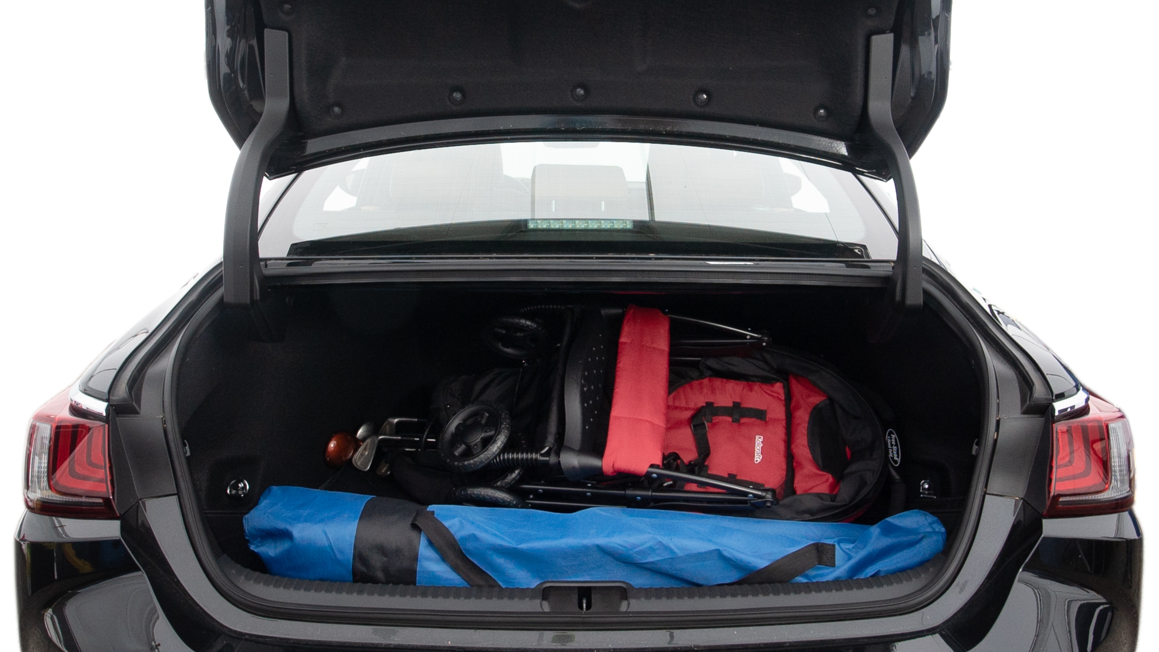 The trunk lid is open showing full view of the trunk. A baby stroller, three grocery carriers, two camping chairs in the carrying bag, and a set of golf clubs are placed inside.
