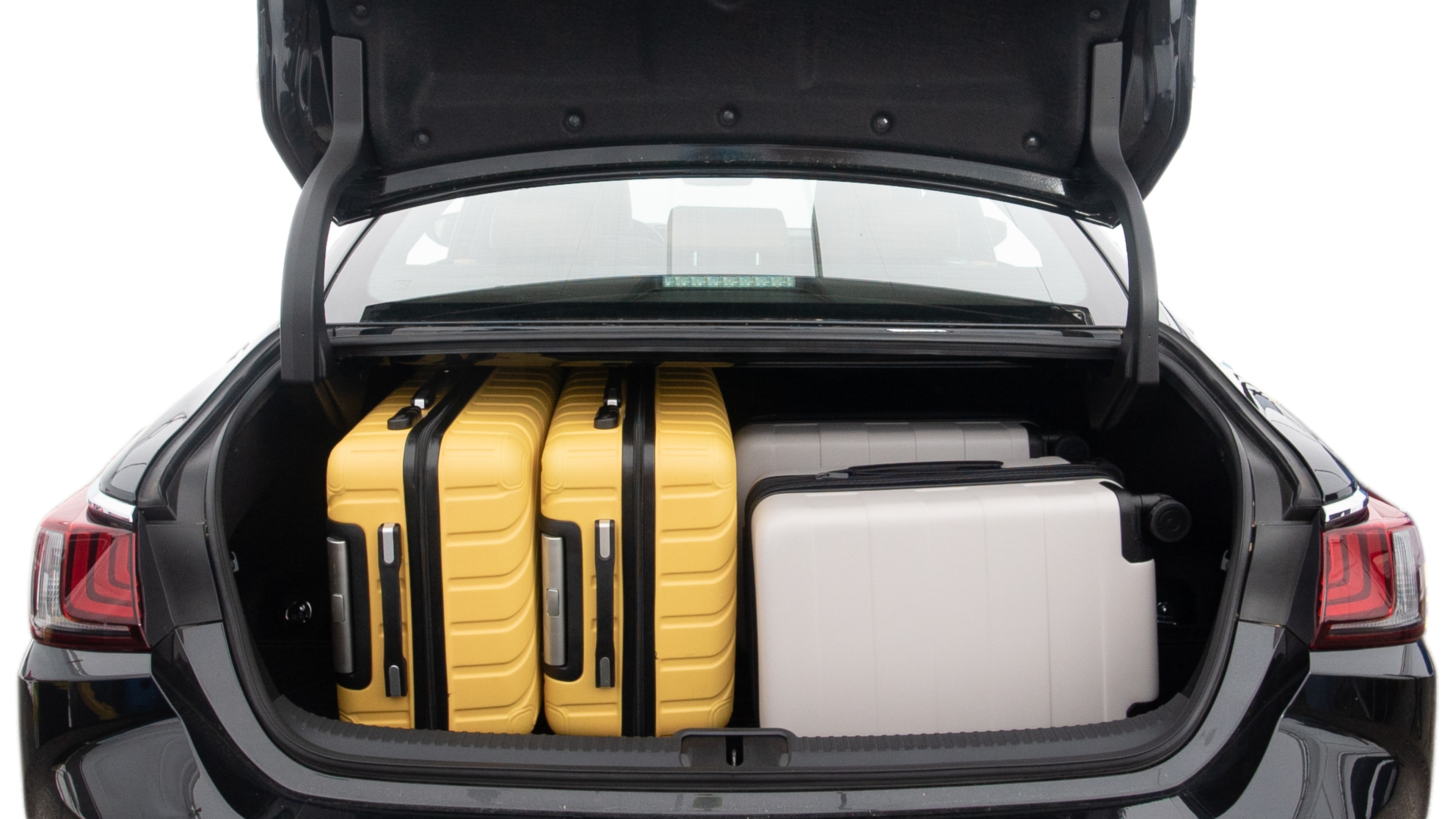 The trunk lid is open, showing full view of the trunk space. Two large and two small suitcases are placed inside.