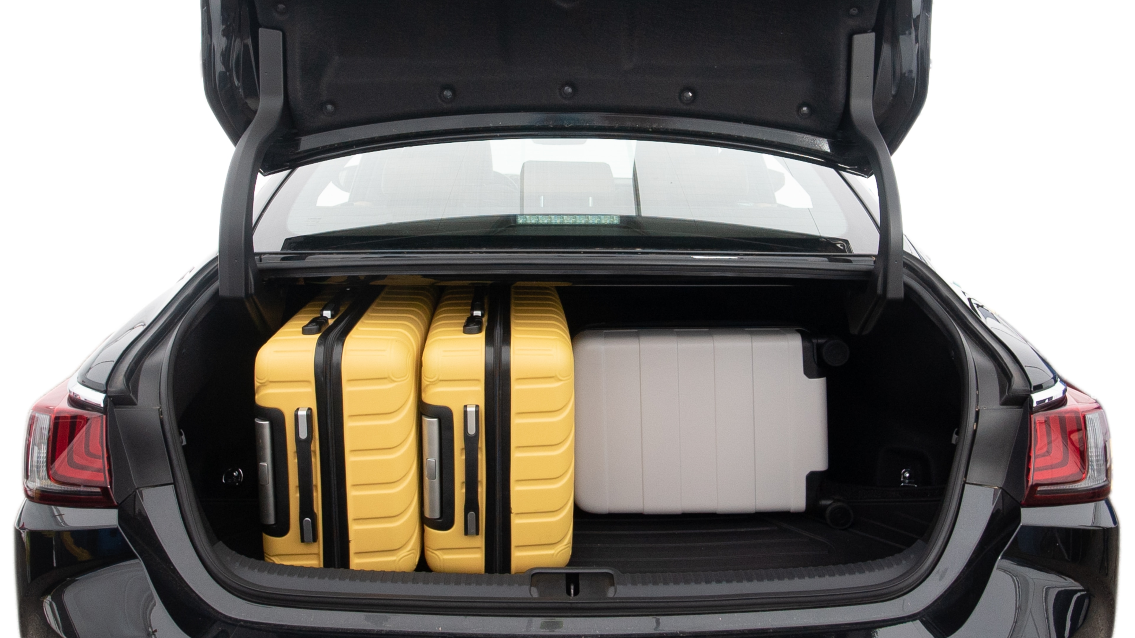 The trunk lid is open, showing full view of the trunk space. Two large and two small suitcases are placed inside.