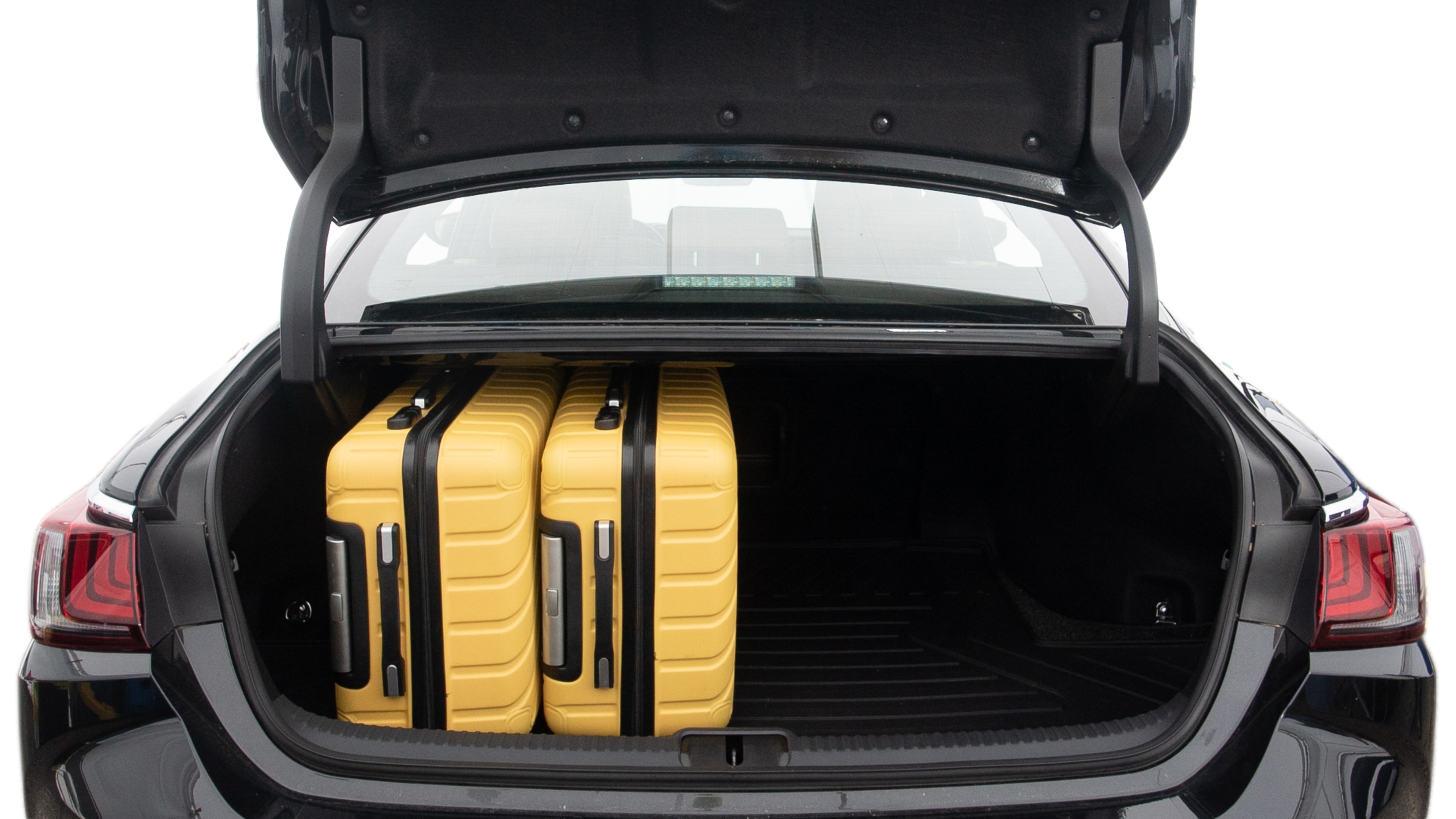 The trunk lid is open, showing full view of the trunk space. Two large and two small suitcases are placed inside.