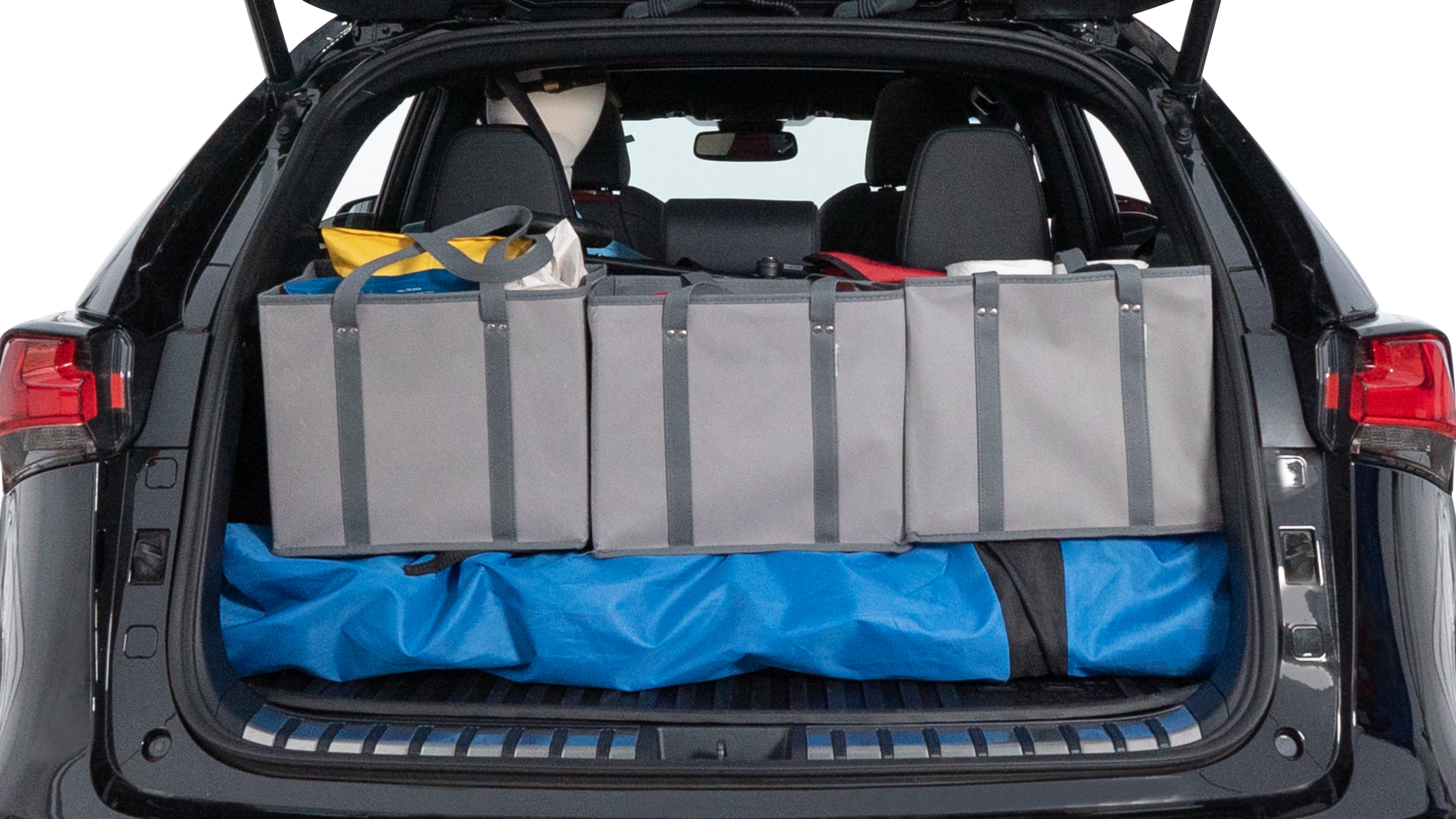 The trunk lid is open showing full view of the trunk. A baby stroller, three grocery carriers, two camping chairs in the carrying bag, and a set of golf clubs are placed inside.