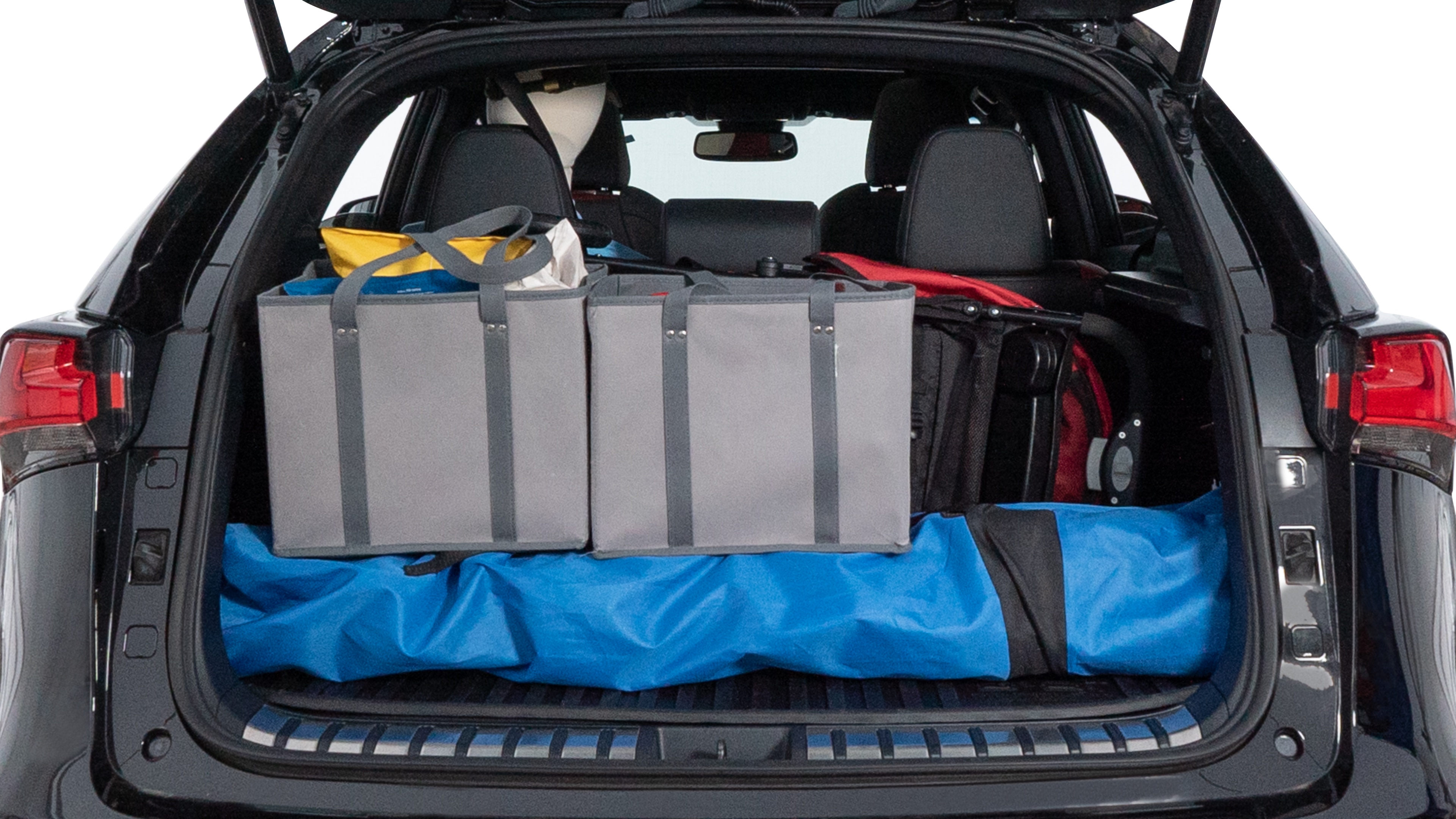 The trunk lid is open showing full view of the trunk. A baby stroller, three grocery carriers, two camping chairs in the carrying bag, and a set of golf clubs are placed inside.