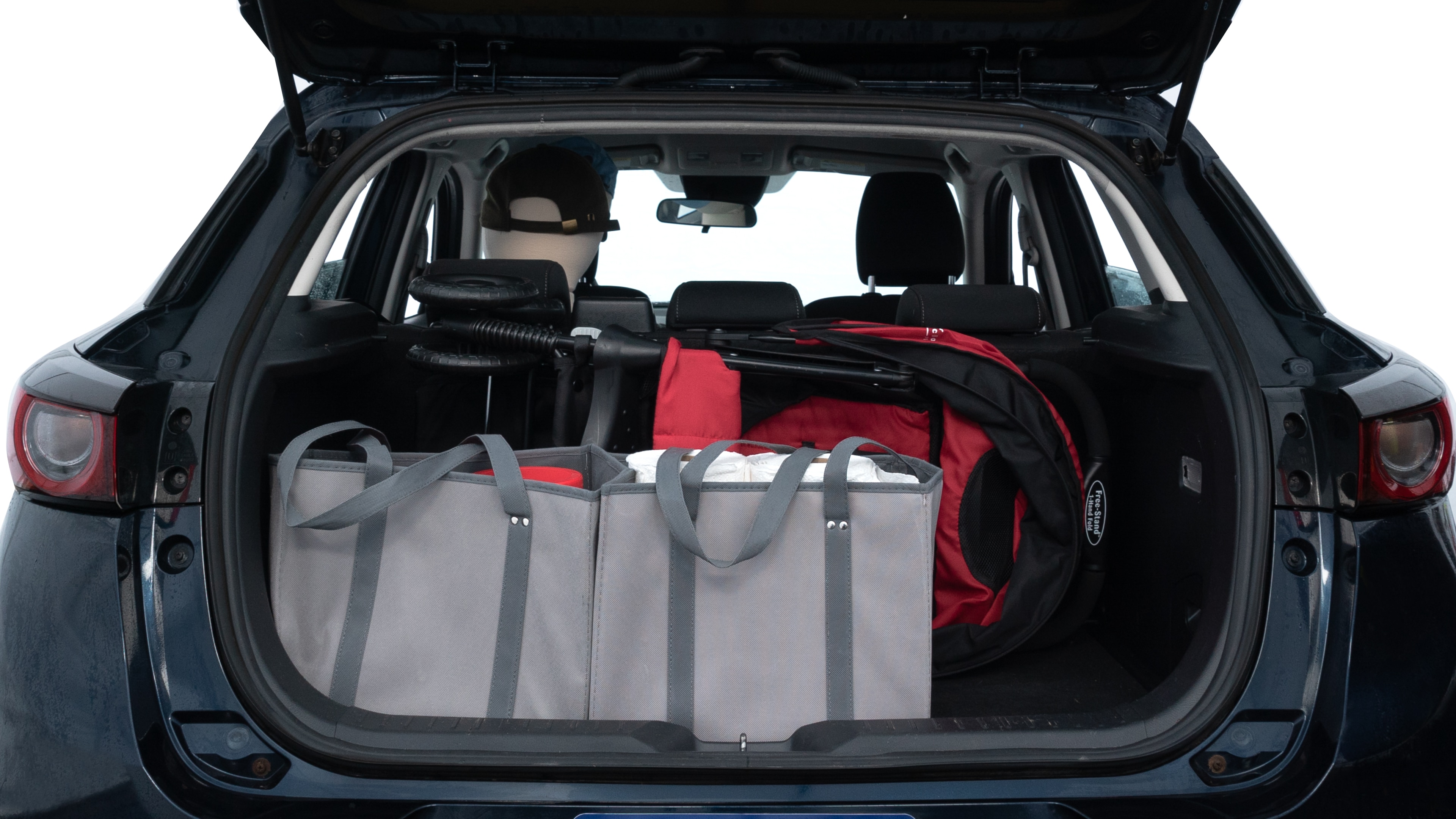 The trunk lid is open showing full view of the trunk. A baby stroller, three grocery carriers, two camping chairs in the carrying bag, and a set of golf clubs are placed inside.