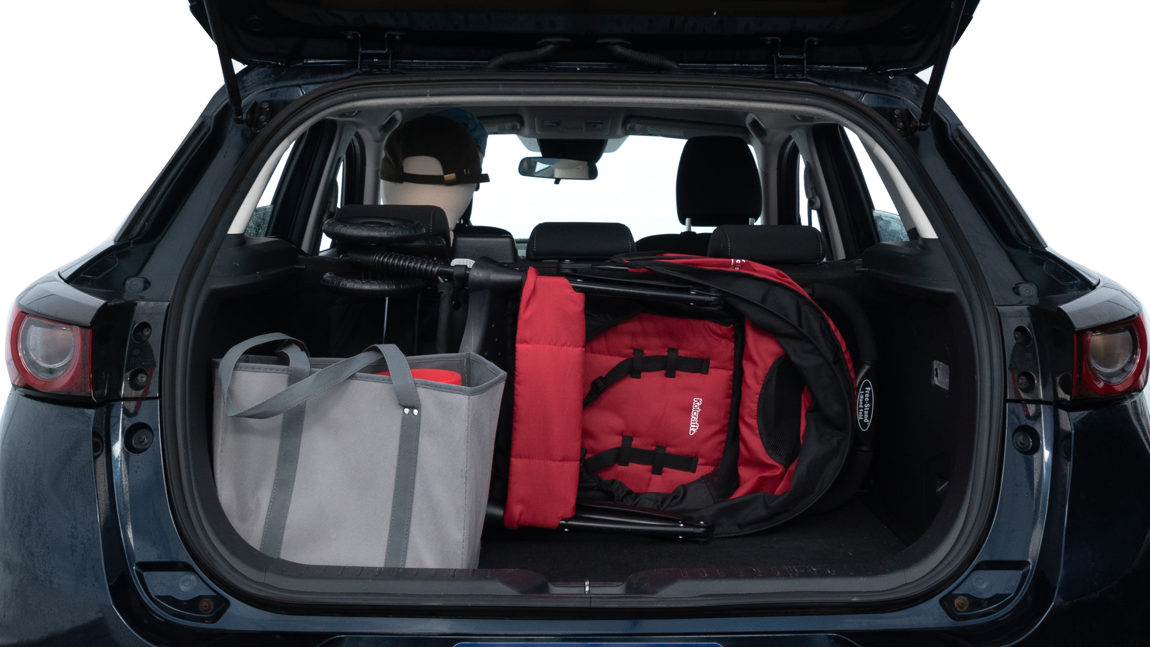 The trunk lid is open showing full view of the trunk. A baby stroller, three grocery carriers, two camping chairs in the carrying bag, and a set of golf clubs are placed inside.
