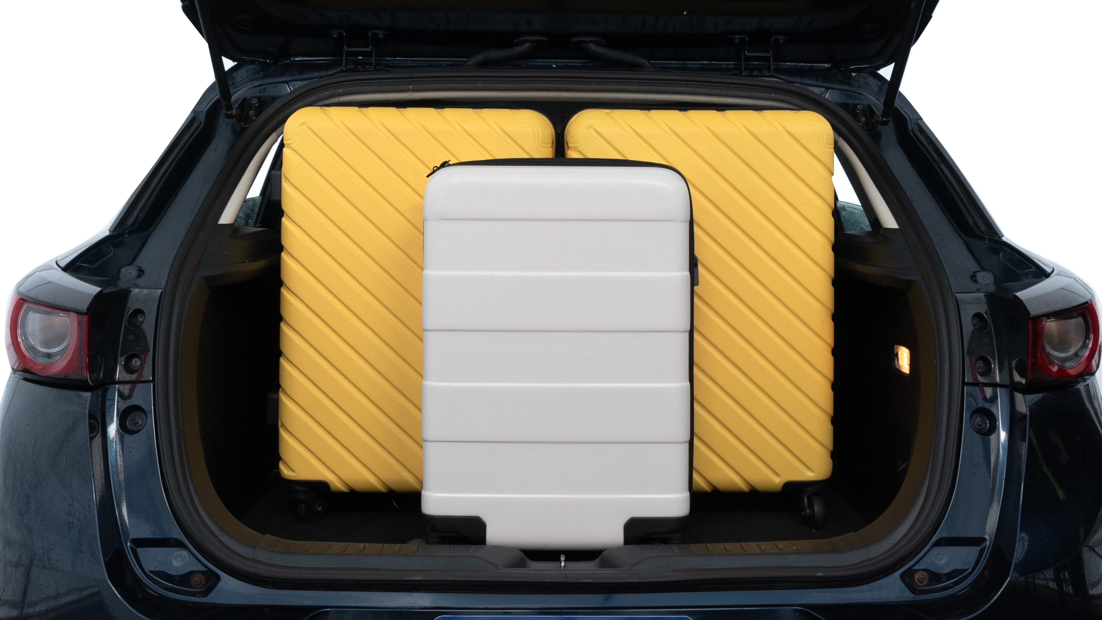 The trunk lid is open, showing full view of the trunk space. Two medium and one small suitcases are placed inside.