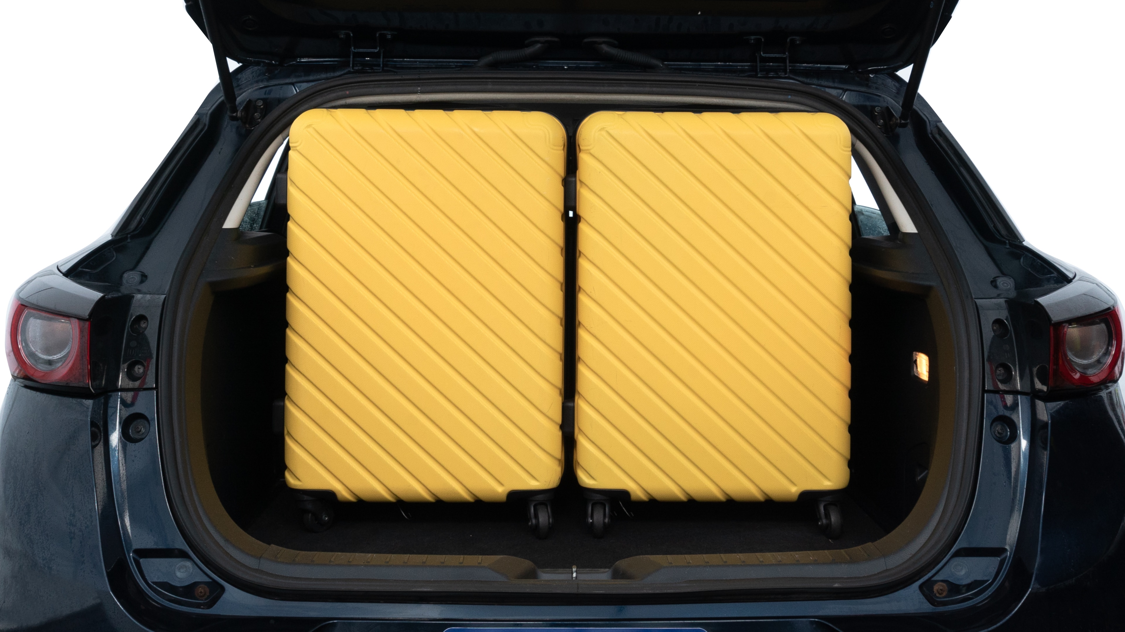 The trunk lid is open, showing full view of the trunk space. Two medium and one small suitcases are placed inside.