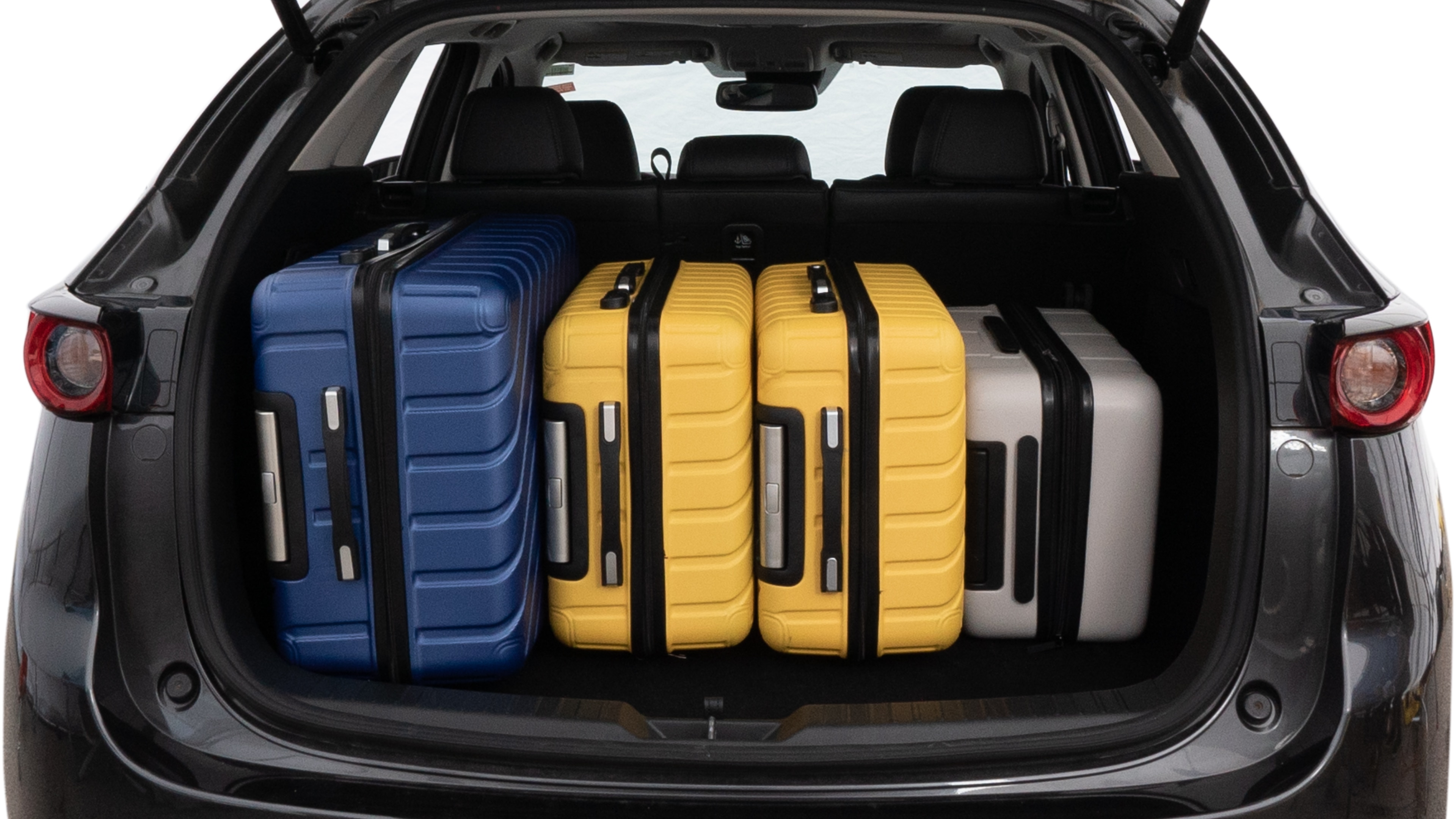 The trunk lid is open, showing full view of the trunk space. One large, two medium, and one small suitcase are placed inside.