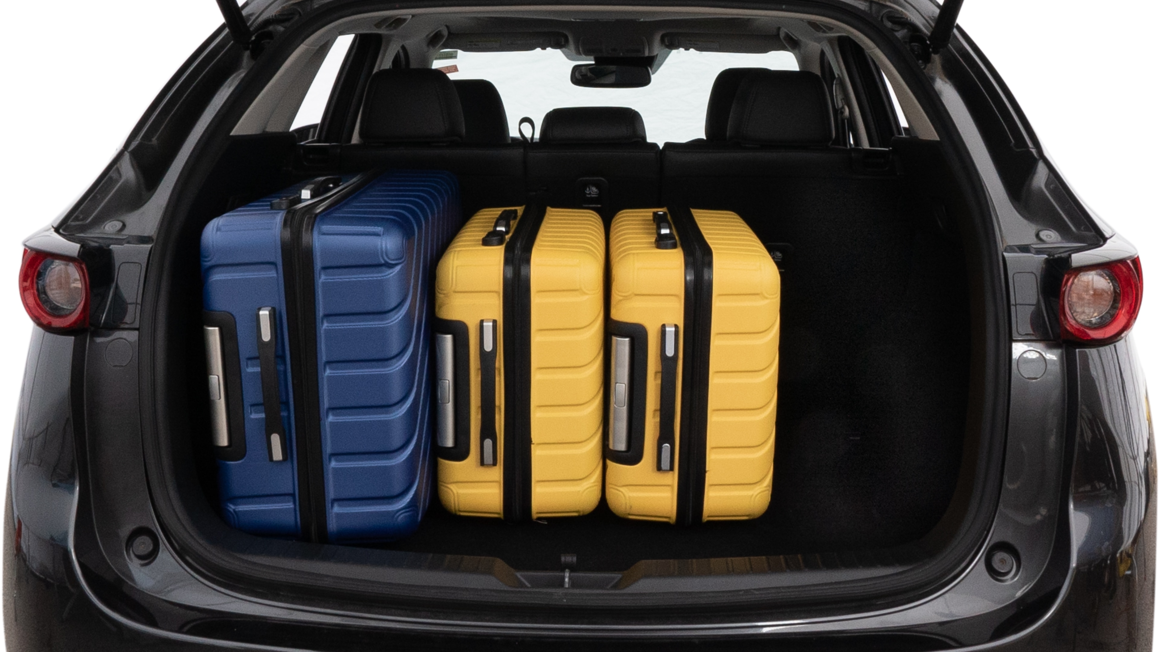 The trunk lid is open, showing full view of the trunk space. One large, two medium, and one small suitcase are placed inside.