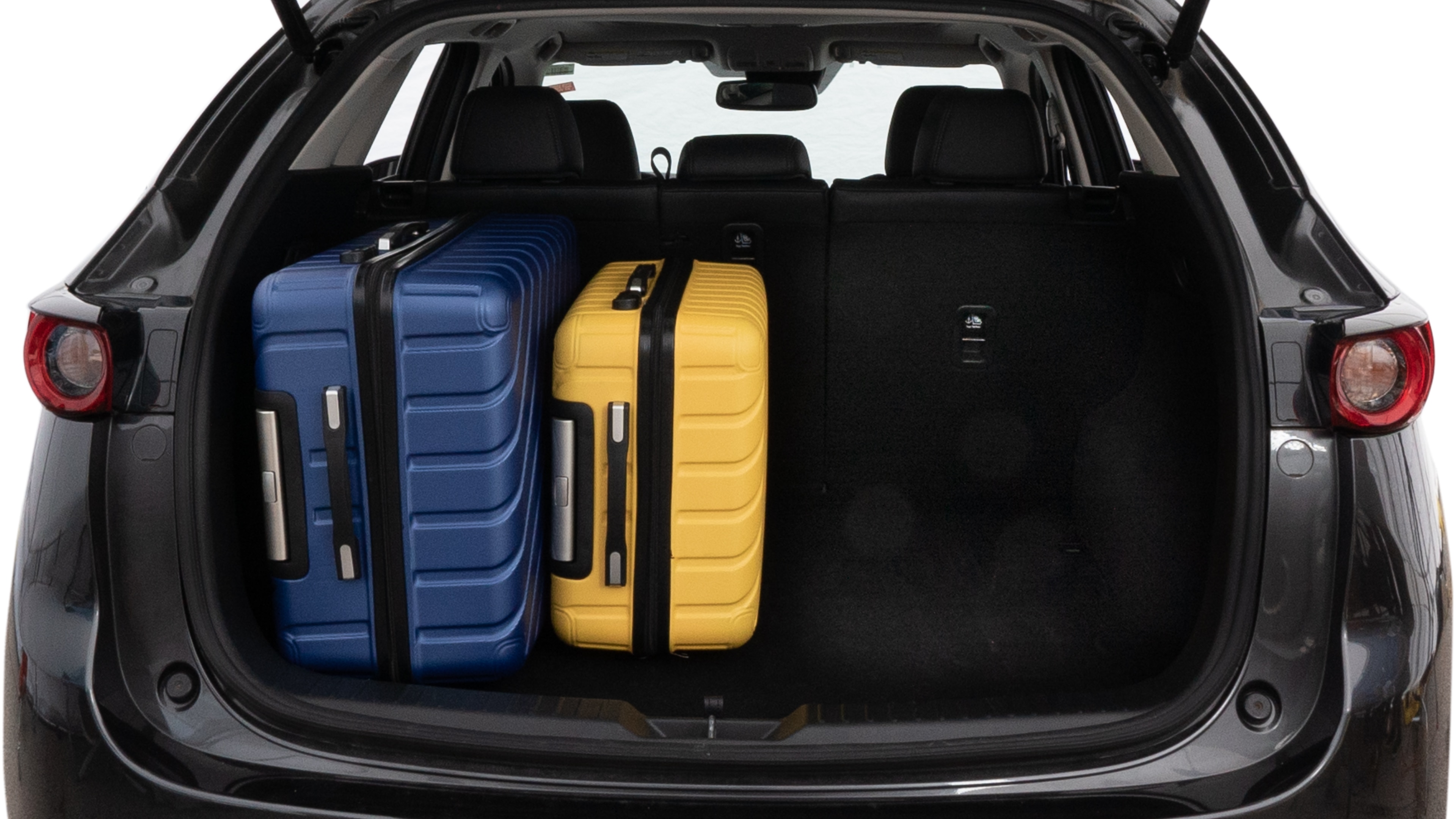 The trunk lid is open, showing full view of the trunk space. One large, two medium, and one small suitcase are placed inside.