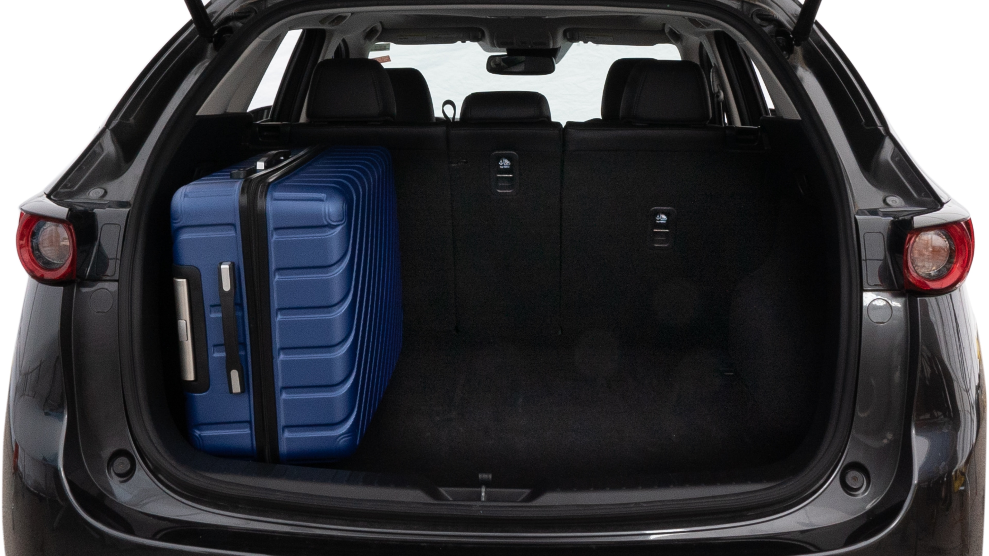 The trunk lid is open, showing full view of the trunk space. One large, two medium, and one small suitcase are placed inside.