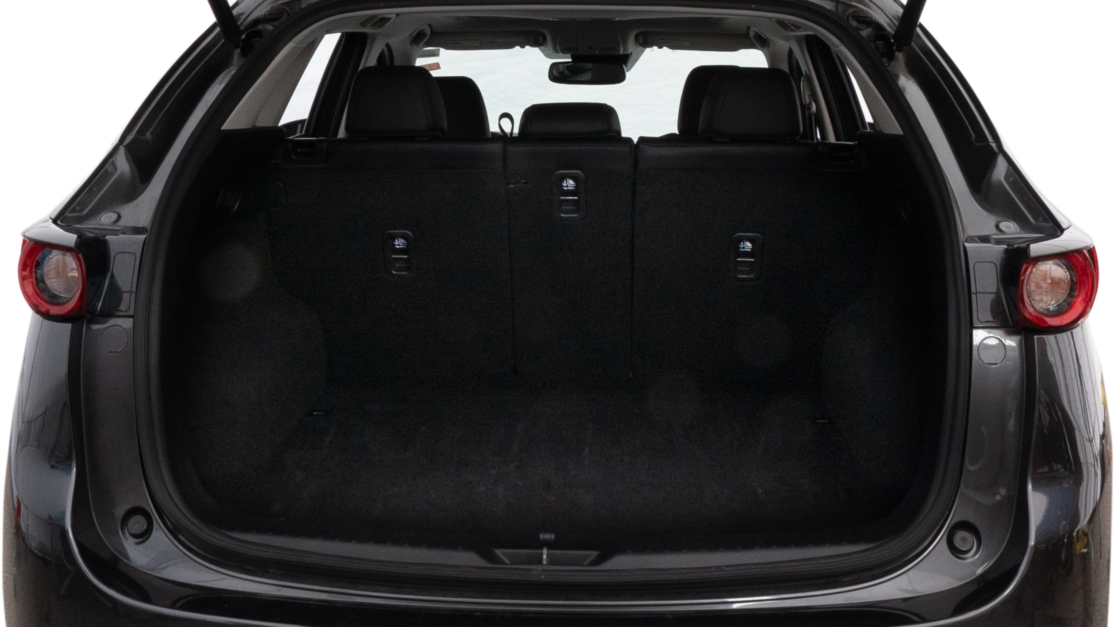 The trunk lid is open, showing full view of the trunk space. One large, two medium, and one small suitcase are placed inside.