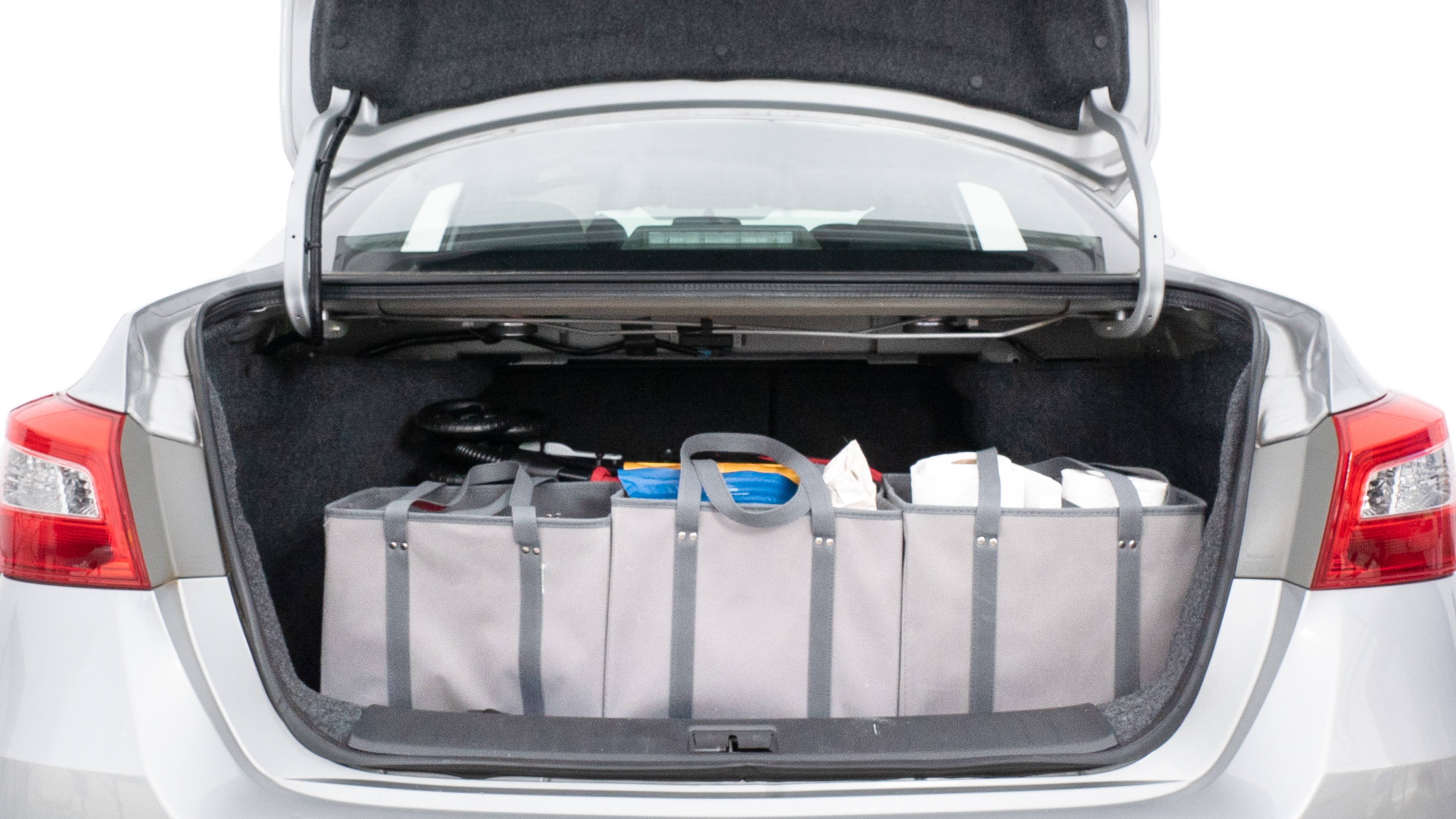 The trunk lid is open showing full view of the trunk. A baby stroller, three grocery carriers, two camping chairs in the carrying bag, and a set of golf clubs are placed inside.