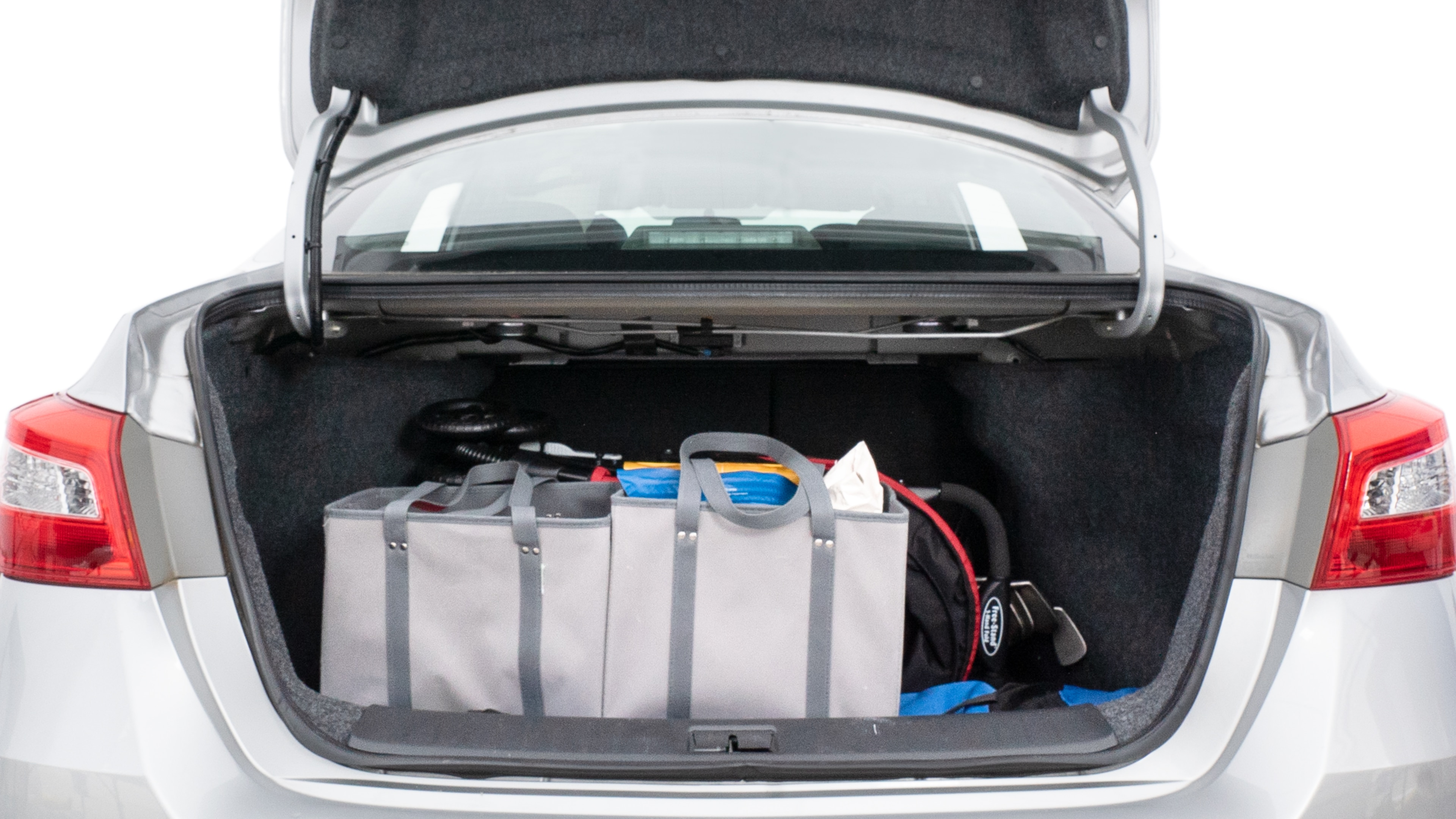 The trunk lid is open showing full view of the trunk. A baby stroller, three grocery carriers, two camping chairs in the carrying bag, and a set of golf clubs are placed inside.