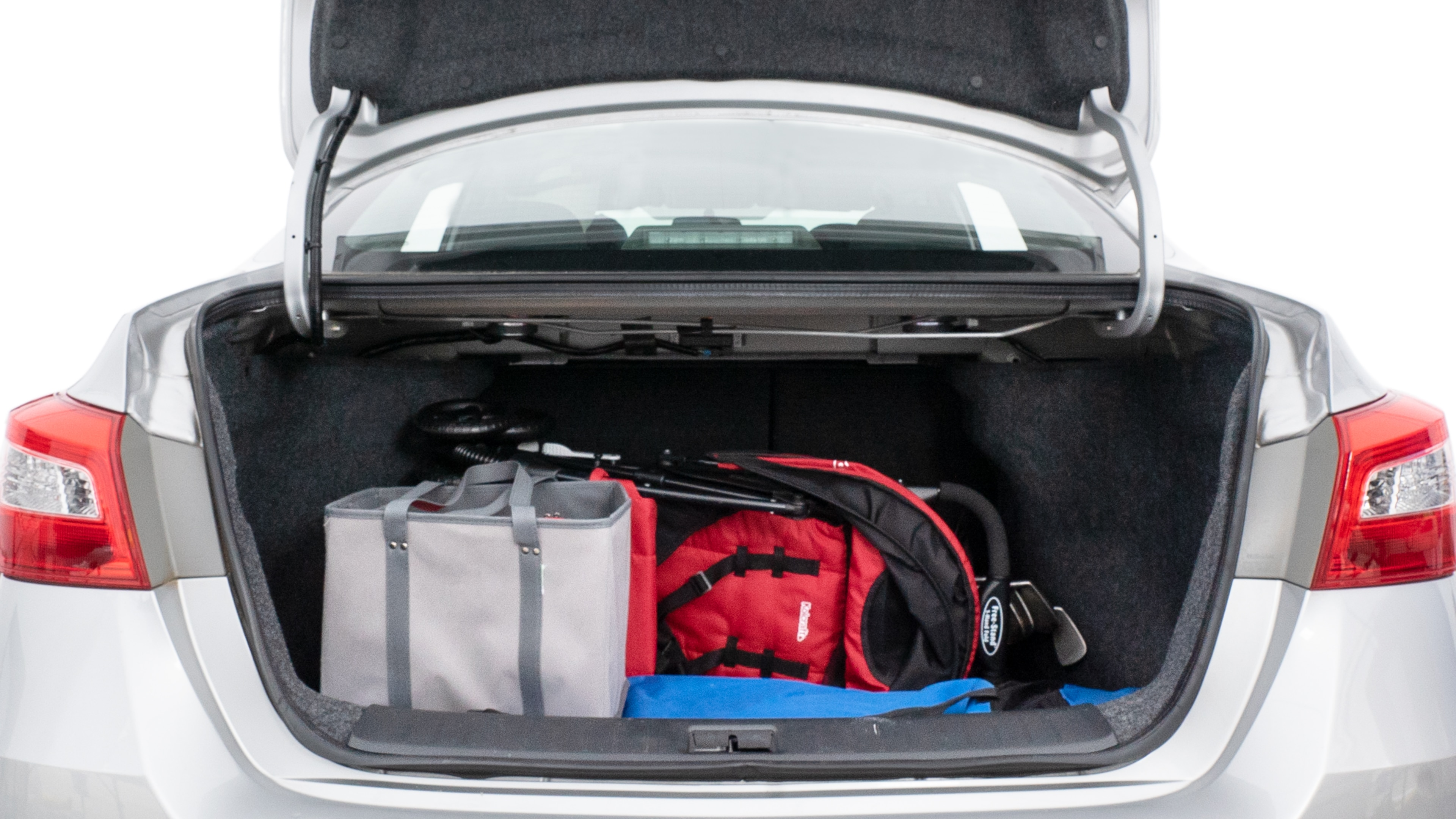 The trunk lid is open showing full view of the trunk. A baby stroller, three grocery carriers, two camping chairs in the carrying bag, and a set of golf clubs are placed inside.
