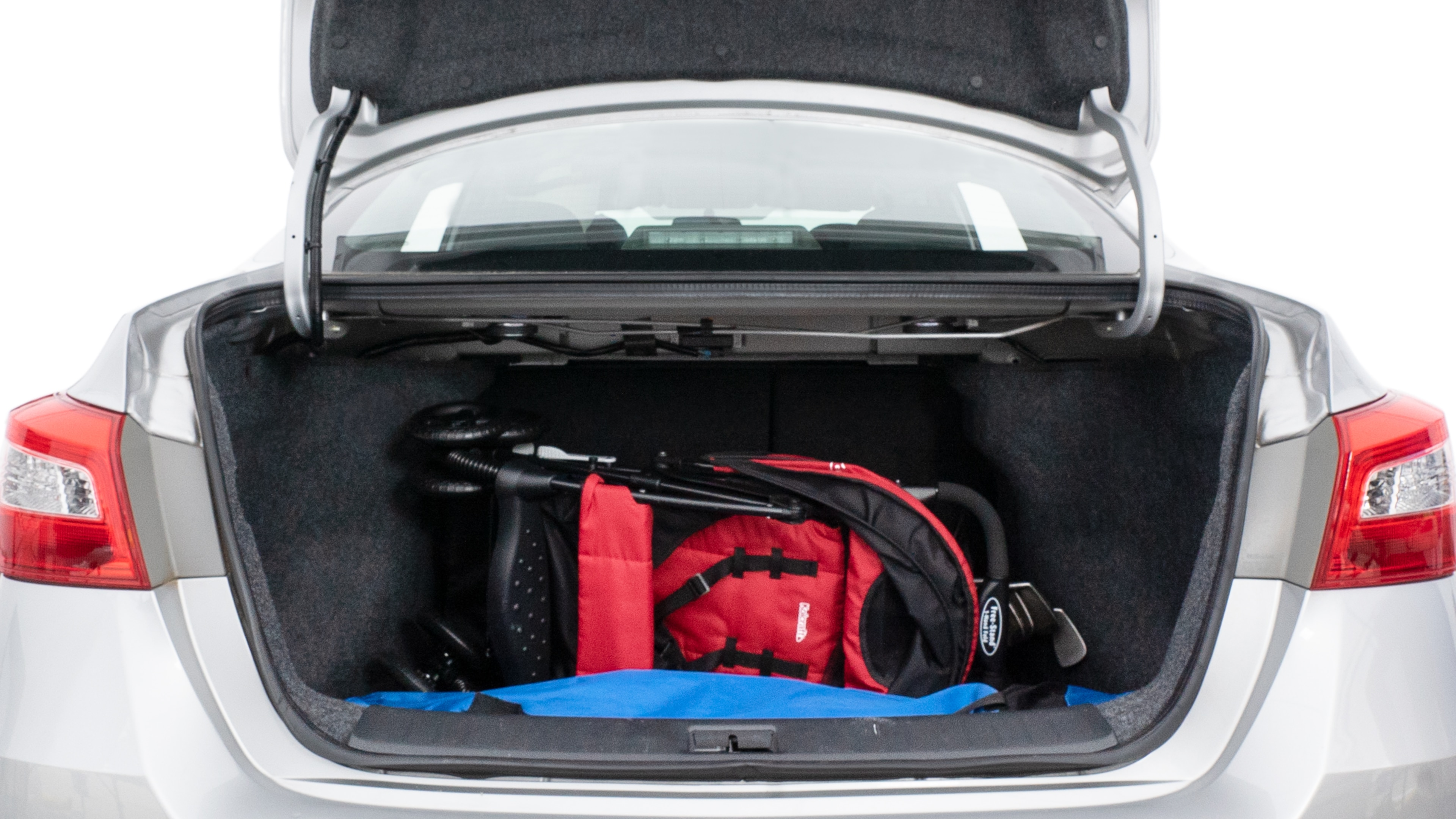 The trunk lid is open showing full view of the trunk. A baby stroller, three grocery carriers, two camping chairs in the carrying bag, and a set of golf clubs are placed inside.