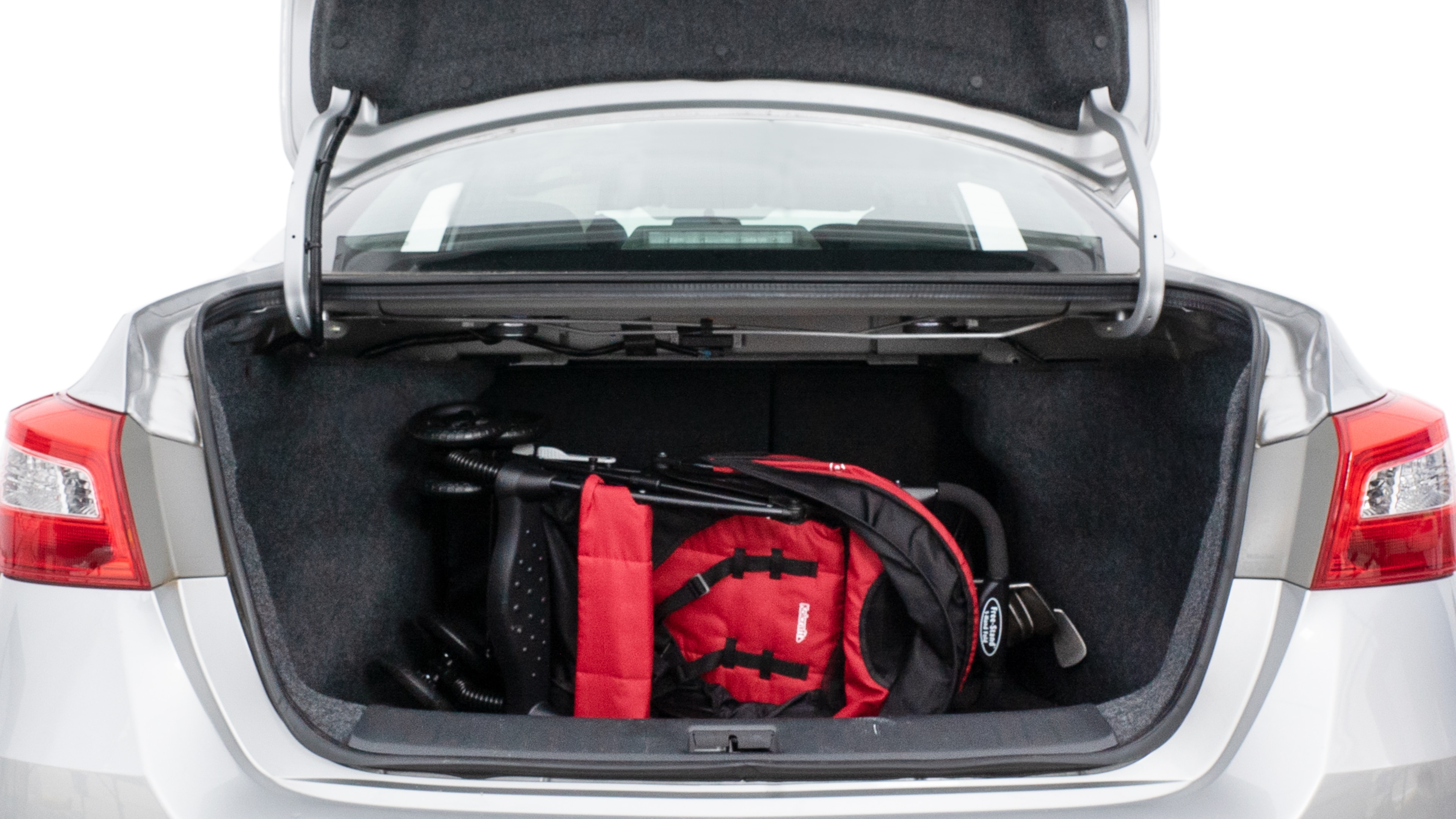 The trunk lid is open showing full view of the trunk. A baby stroller, three grocery carriers, two camping chairs in the carrying bag, and a set of golf clubs are placed inside.