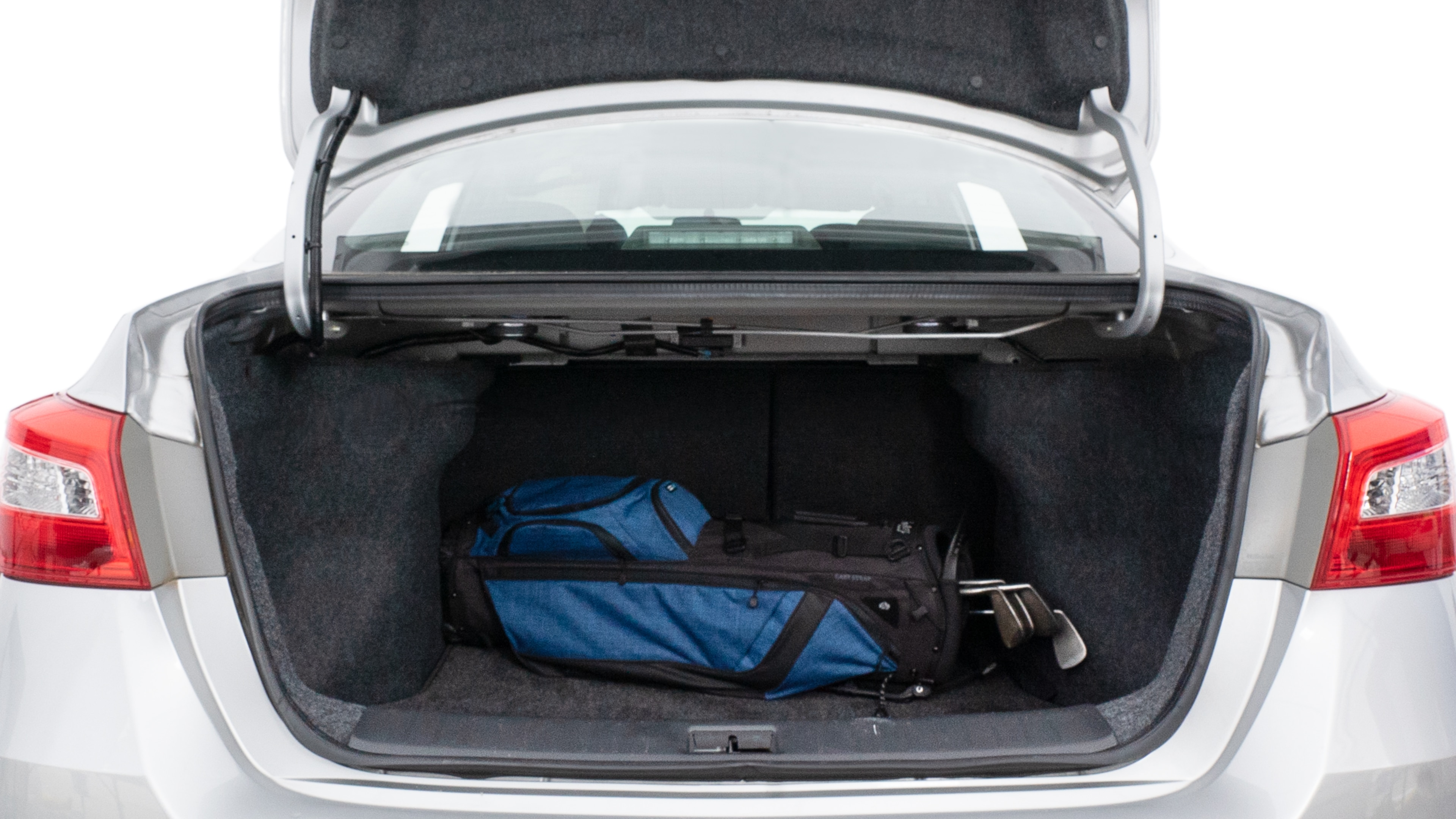 The trunk lid is open showing full view of the trunk. A baby stroller, three grocery carriers, two camping chairs in the carrying bag, and a set of golf clubs are placed inside.