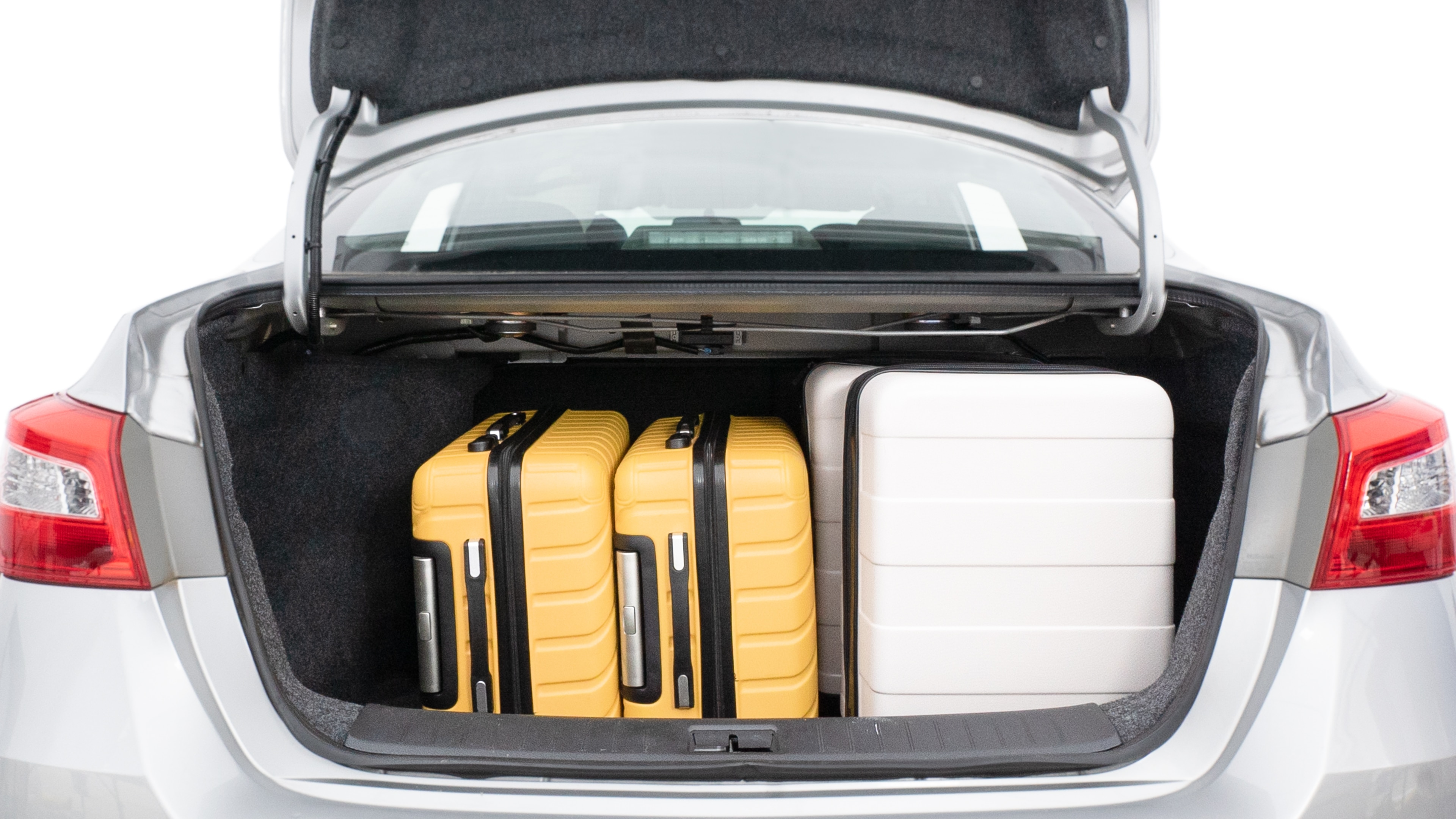 The trunk lid is open, showing full view of the trunk space. Two medium and two small suitcases are placed inside.