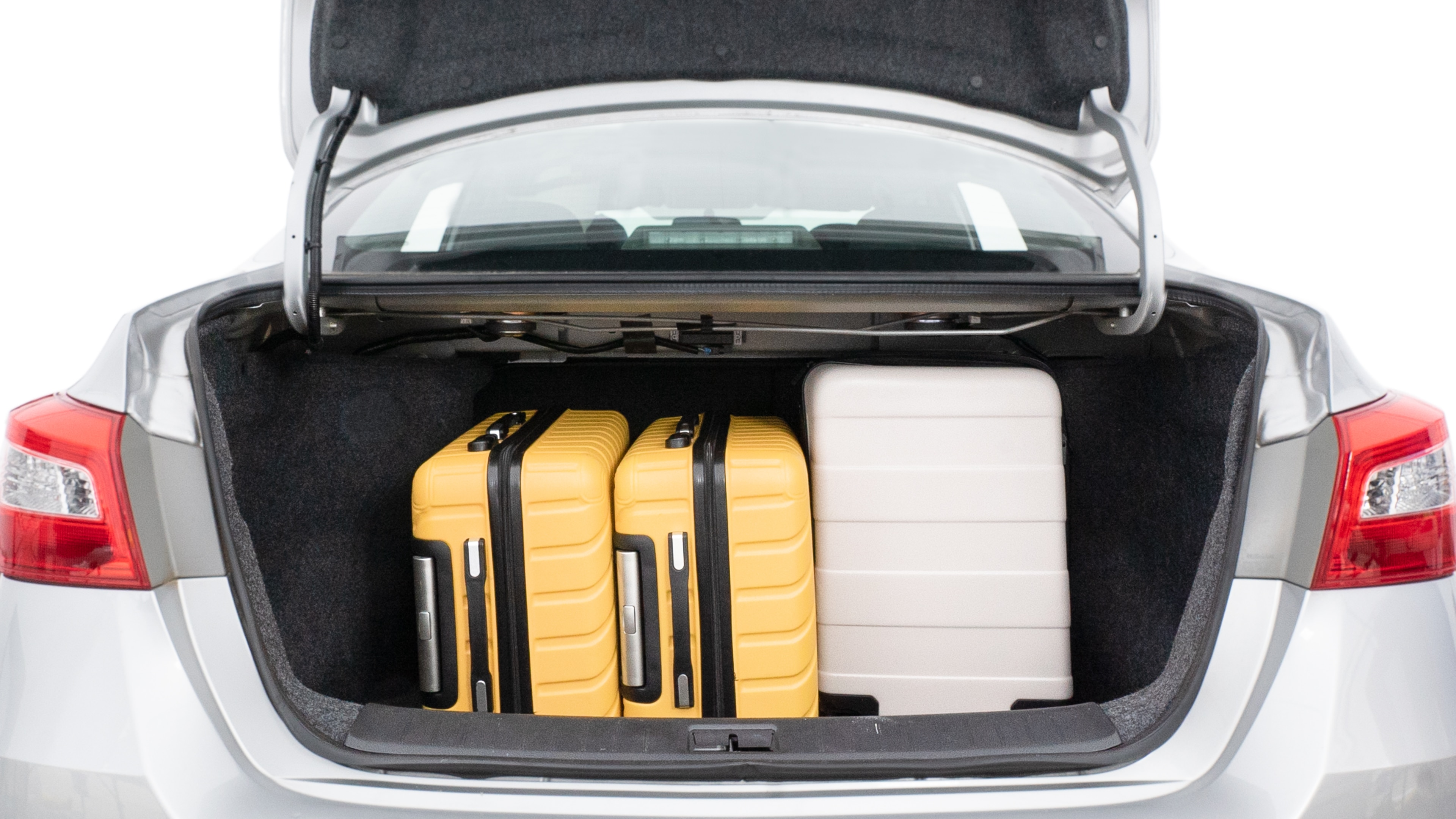 The trunk lid is open, showing full view of the trunk space. Two medium and two small suitcases are placed inside.