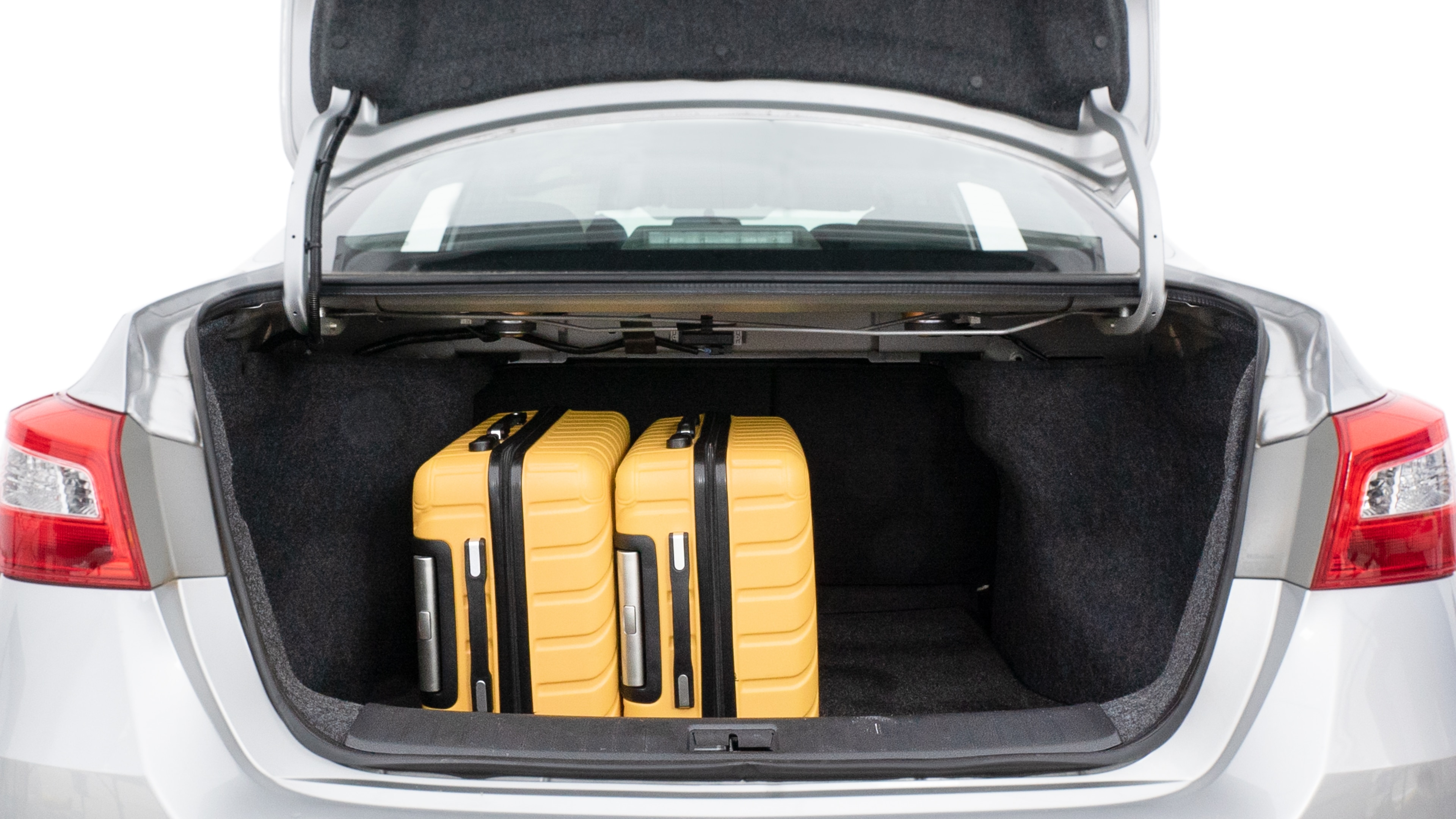 The trunk lid is open, showing full view of the trunk space. Two medium and two small suitcases are placed inside.