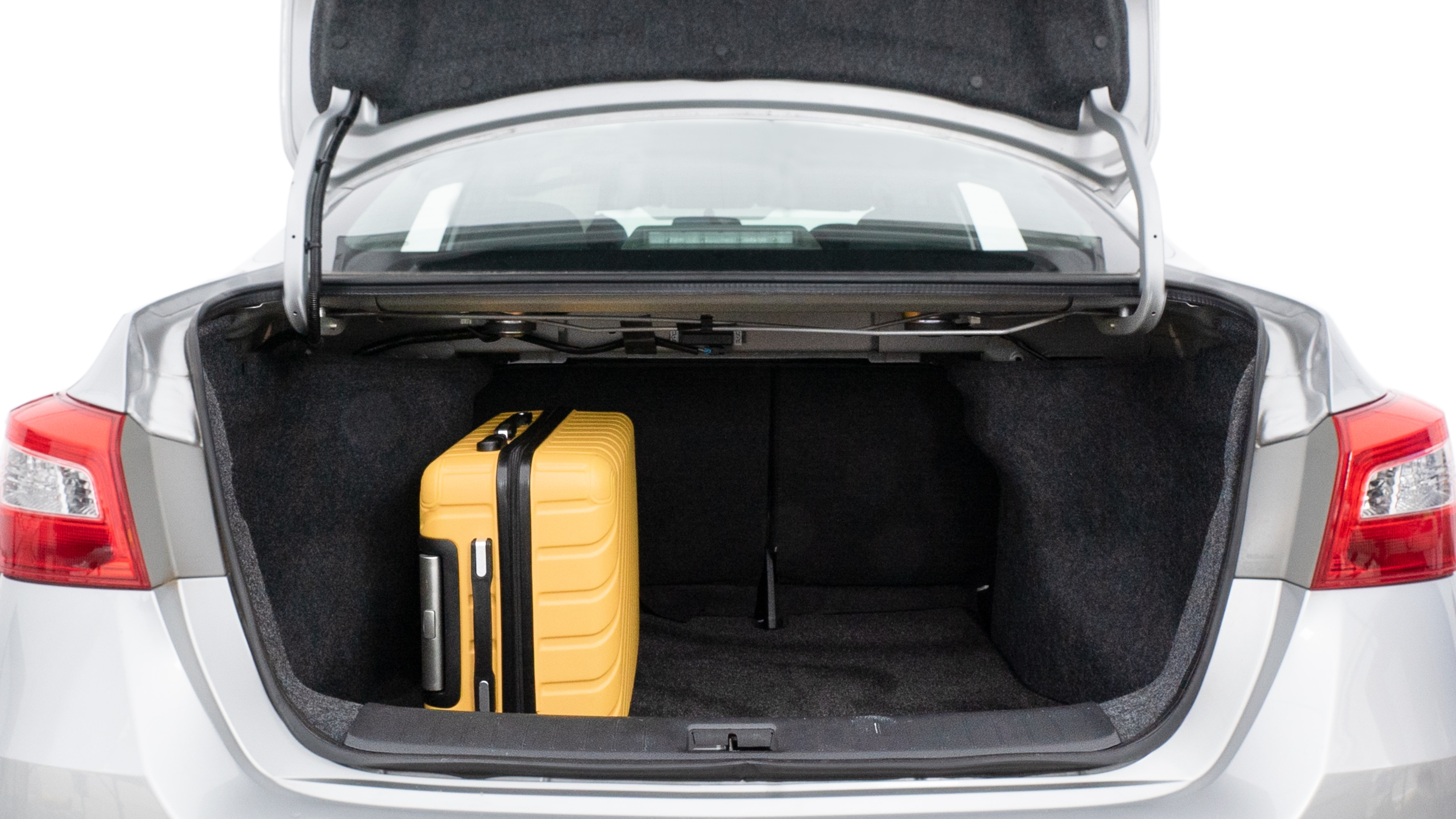 The trunk lid is open, showing full view of the trunk space. Two medium and two small suitcases are placed inside.