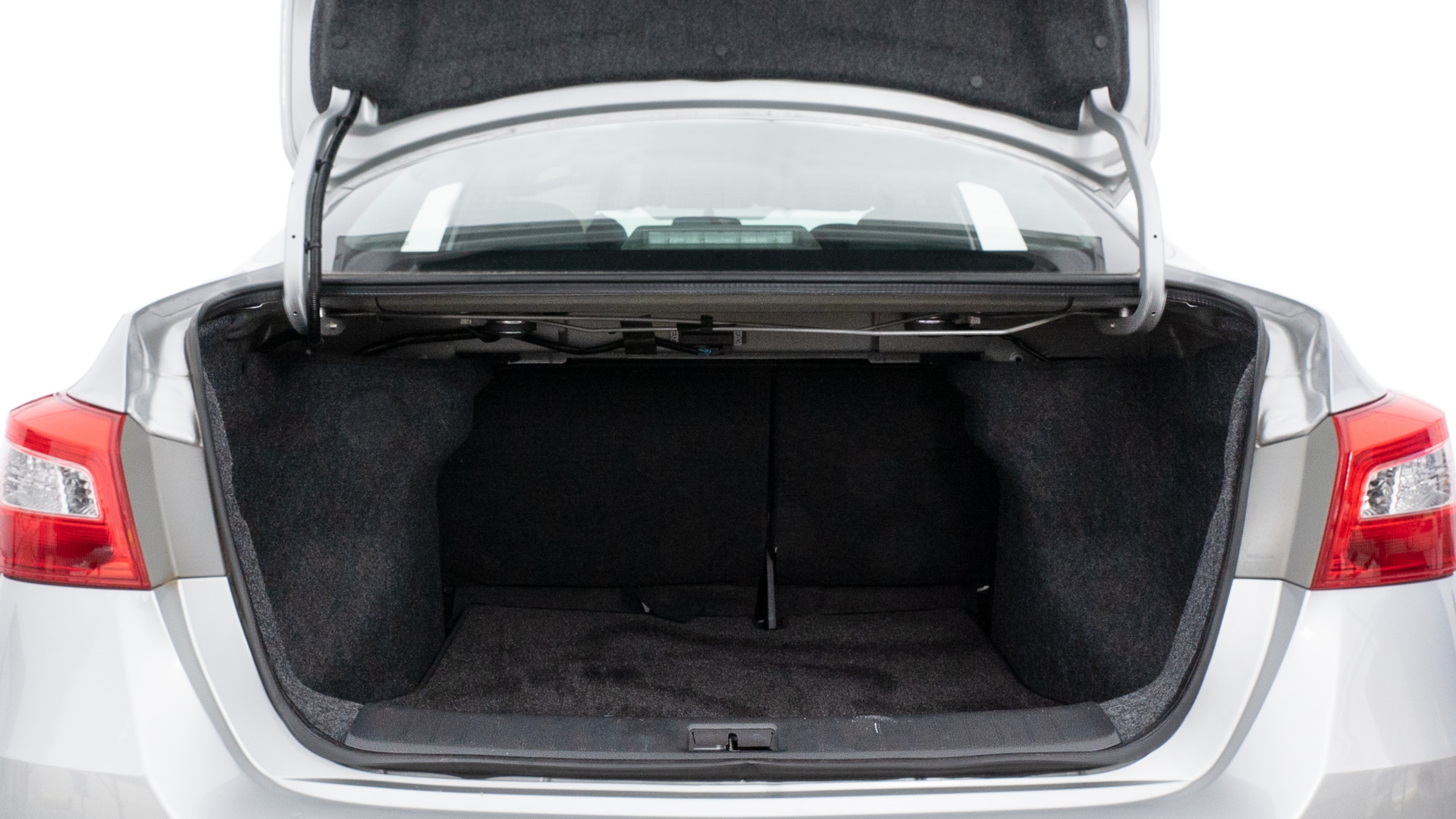 The trunk lid is open, showing full view of the trunk space. Two medium and two small suitcases are placed inside.