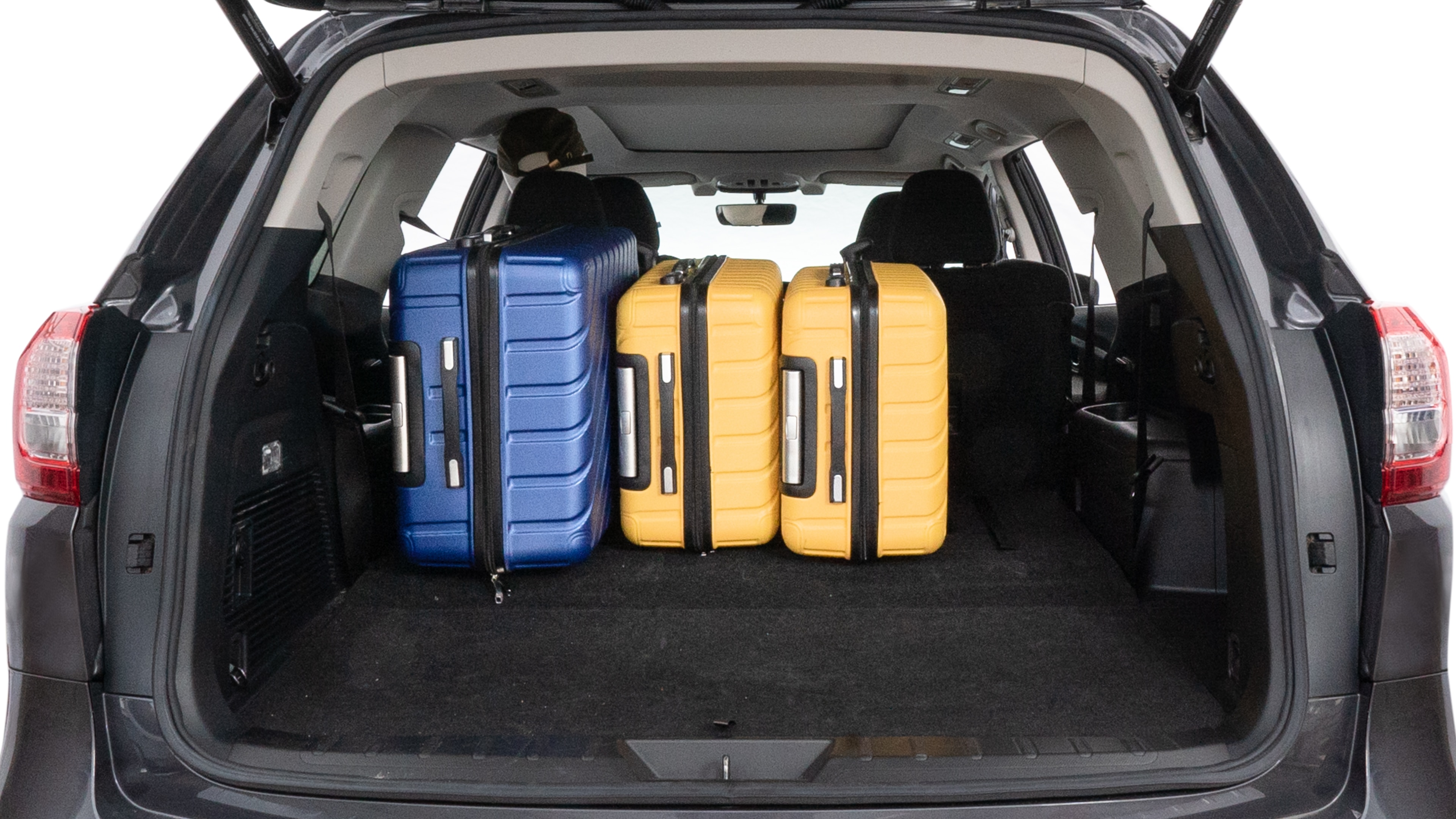The trunk lid is open, showing full view of the trunk space. One large, two medium, and two small suitcases are placed inside.