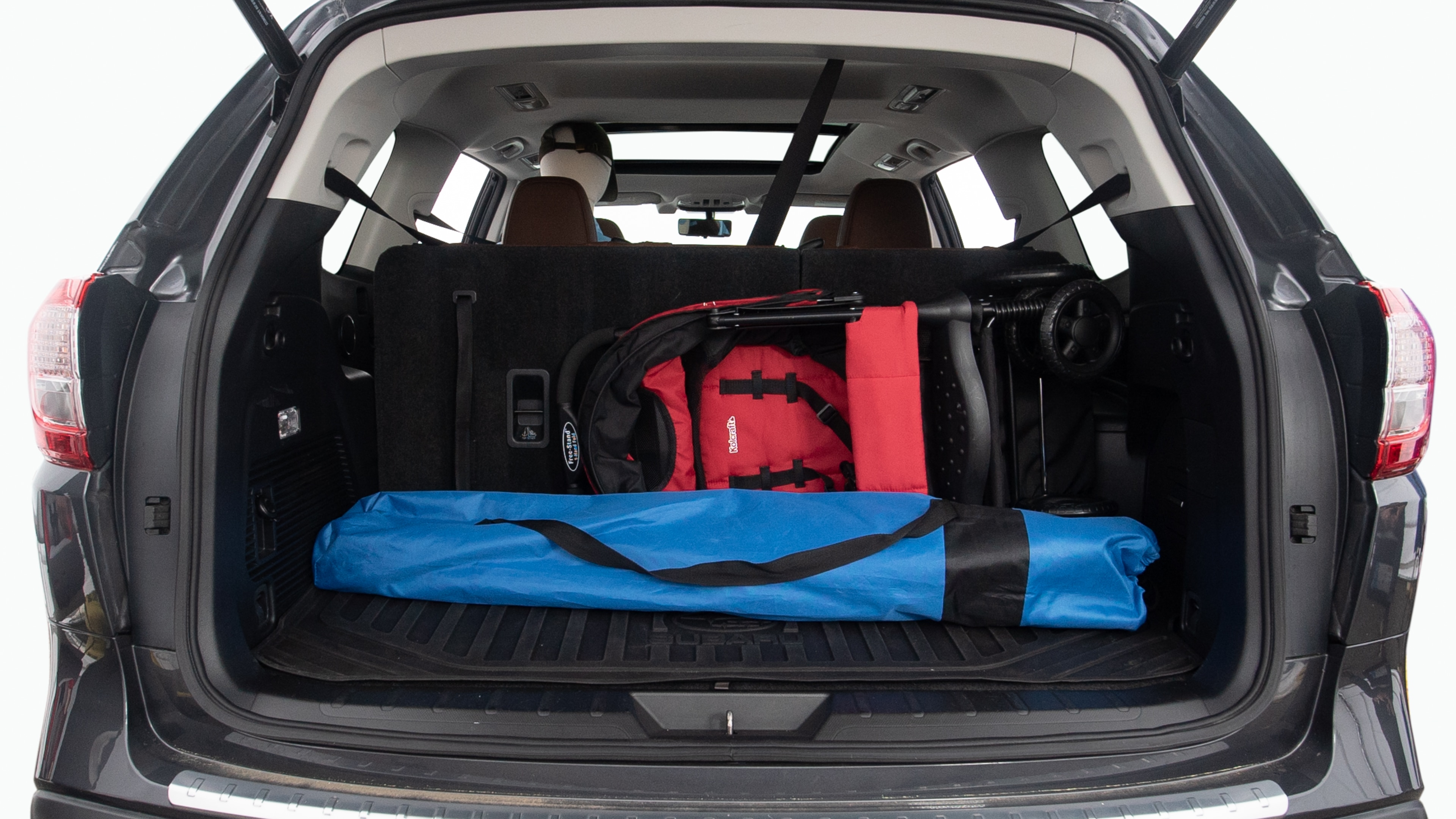 The trunk lid is open showing full view of the trunk. Two grocery carriers, two camping chairs in the carrying bag, and a set of golf clubs are placed inside.
