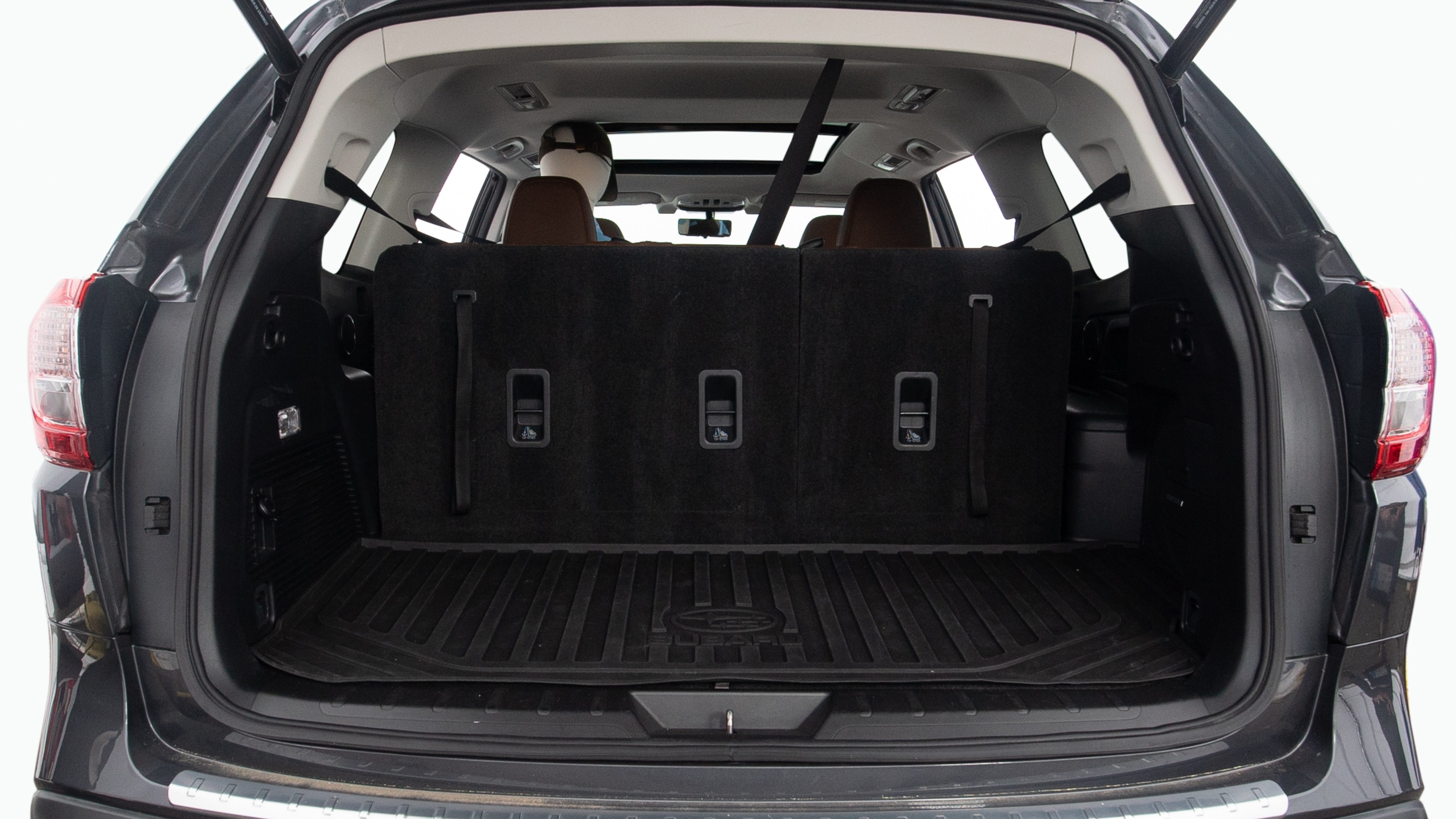 The trunk lid is open showing full view of the trunk. Two grocery carriers, two camping chairs in the carrying bag, and a set of golf clubs are placed inside.