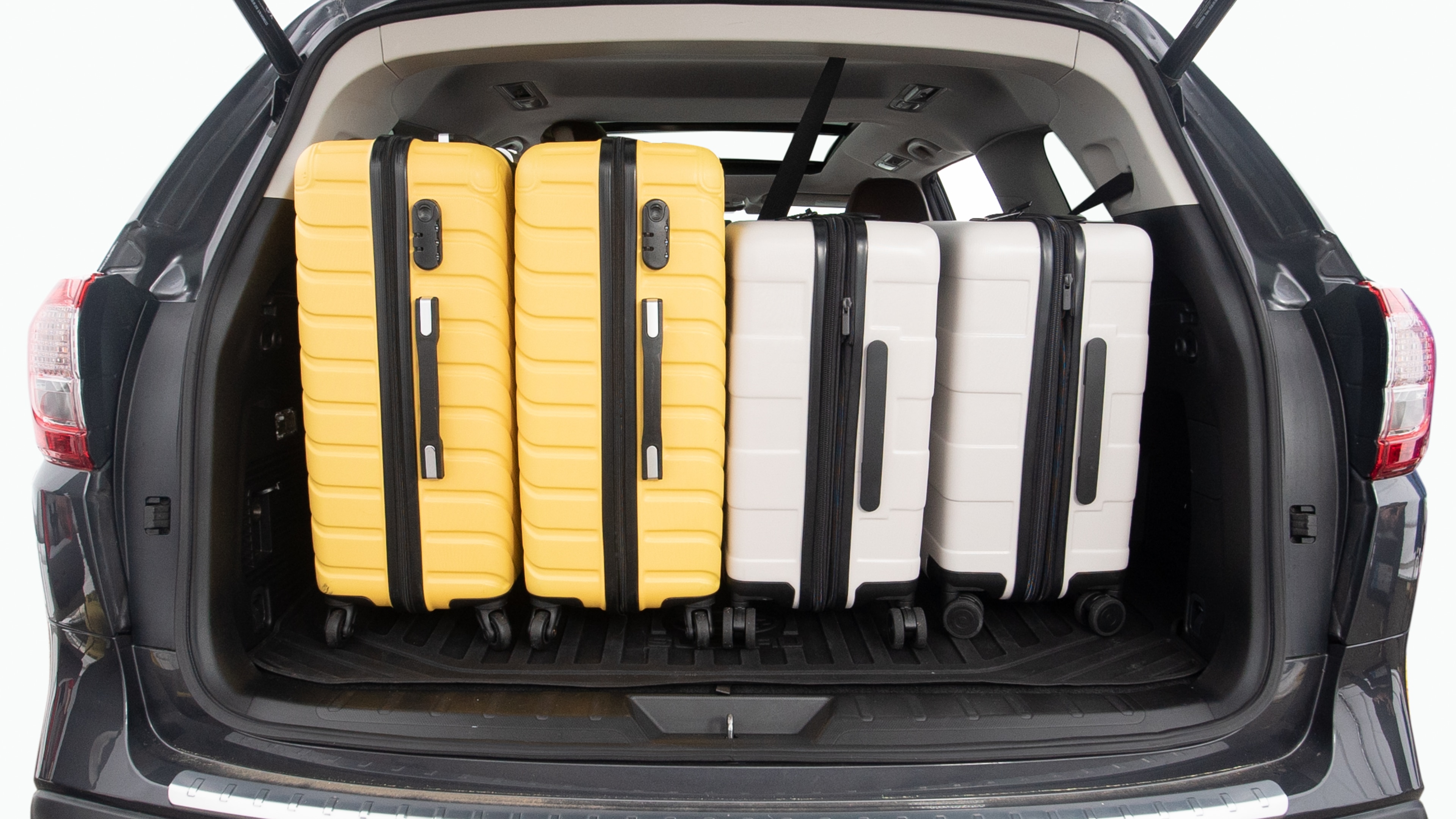 The trunk lid is open, showing full view of the trunk space. Two large and two small suitcases are placed inside.