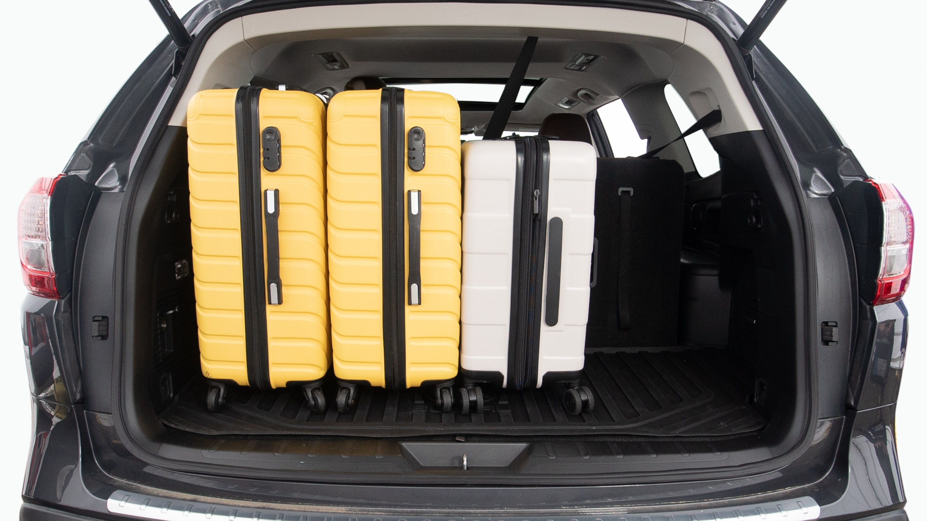 The trunk lid is open, showing full view of the trunk space. Two large and two small suitcases are placed inside.