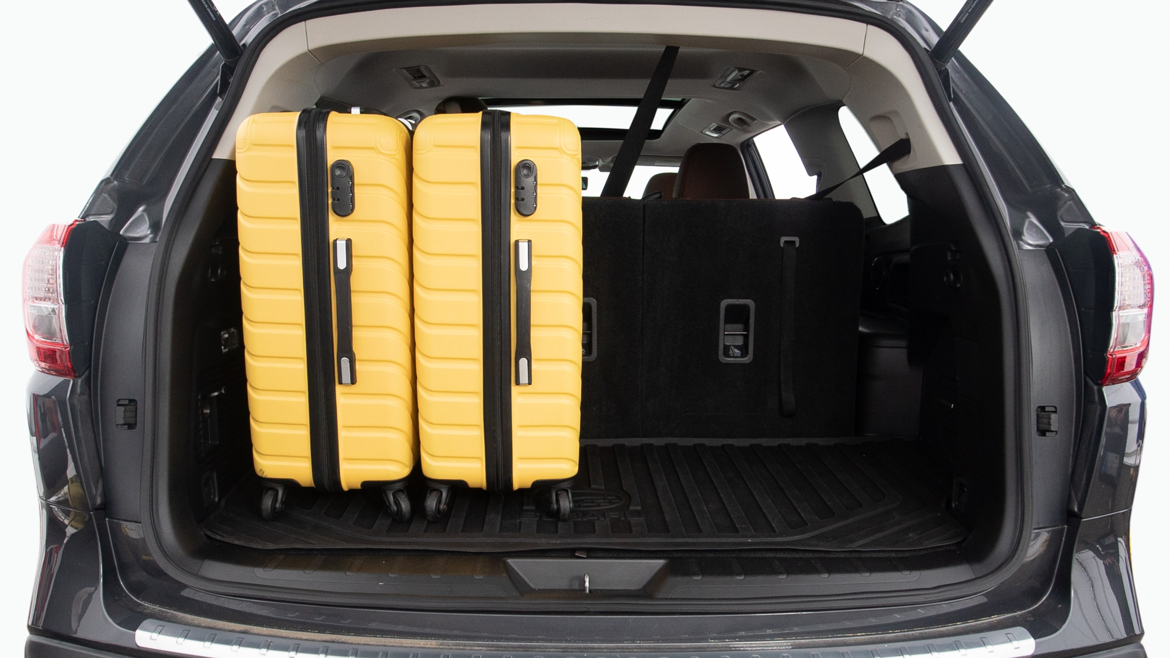 The trunk lid is open, showing full view of the trunk space. Two large and two small suitcases are placed inside.