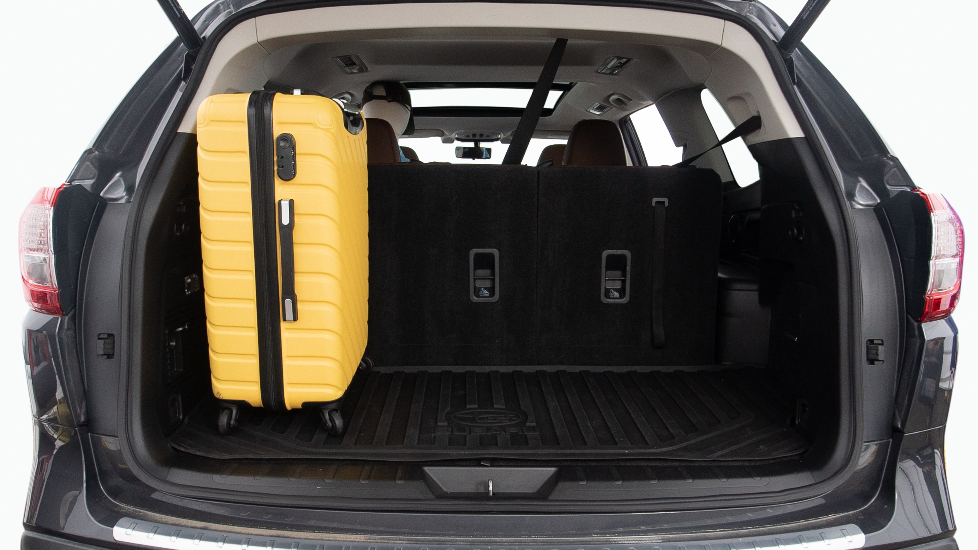 The trunk lid is open, showing full view of the trunk space. Two large and two small suitcases are placed inside.