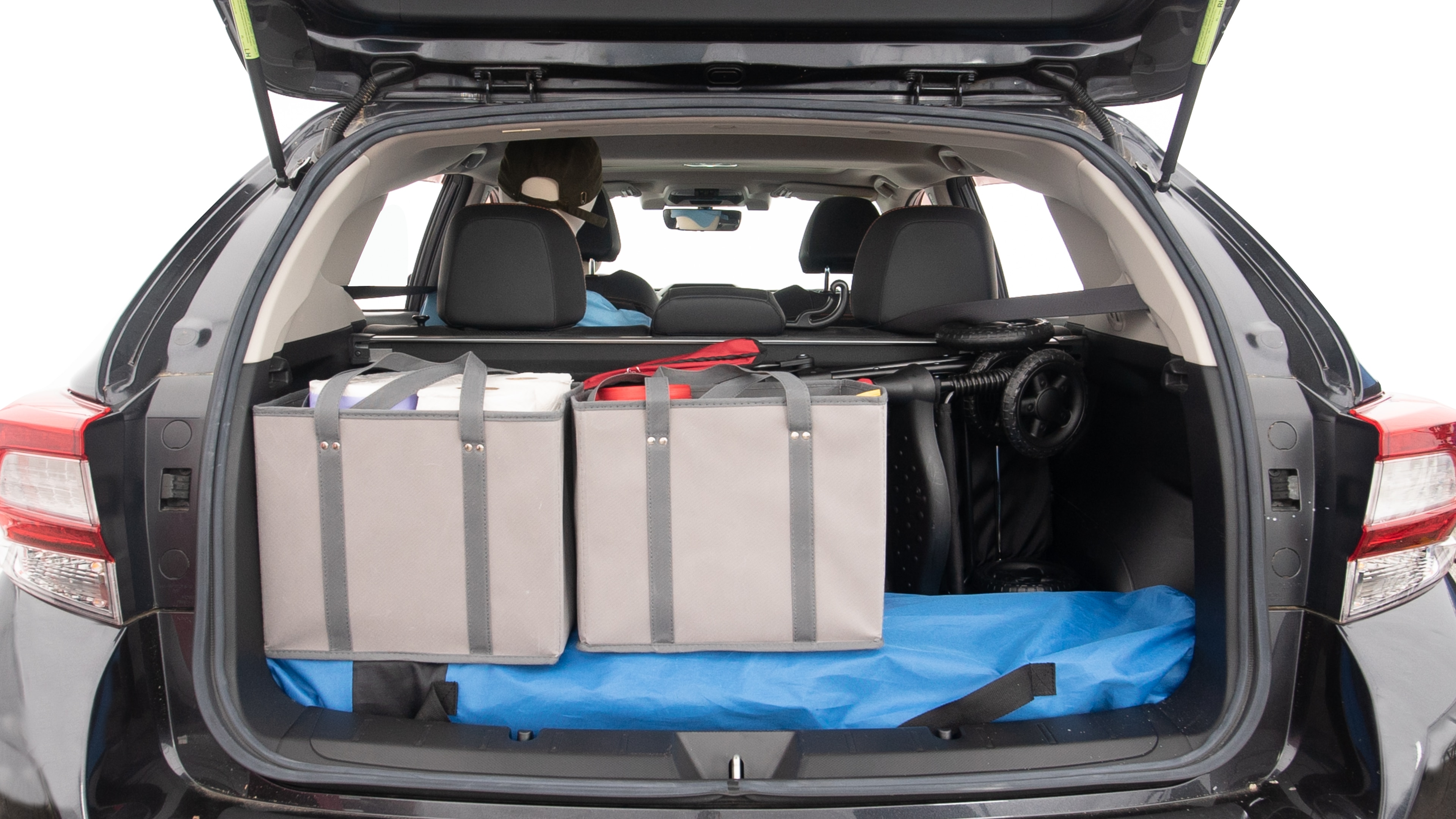 The trunk lid is open showing full view of the trunk. A baby stroller, three grocery carriers, two camping chairs in the carrying bag, and a set of golf clubs are placed inside.