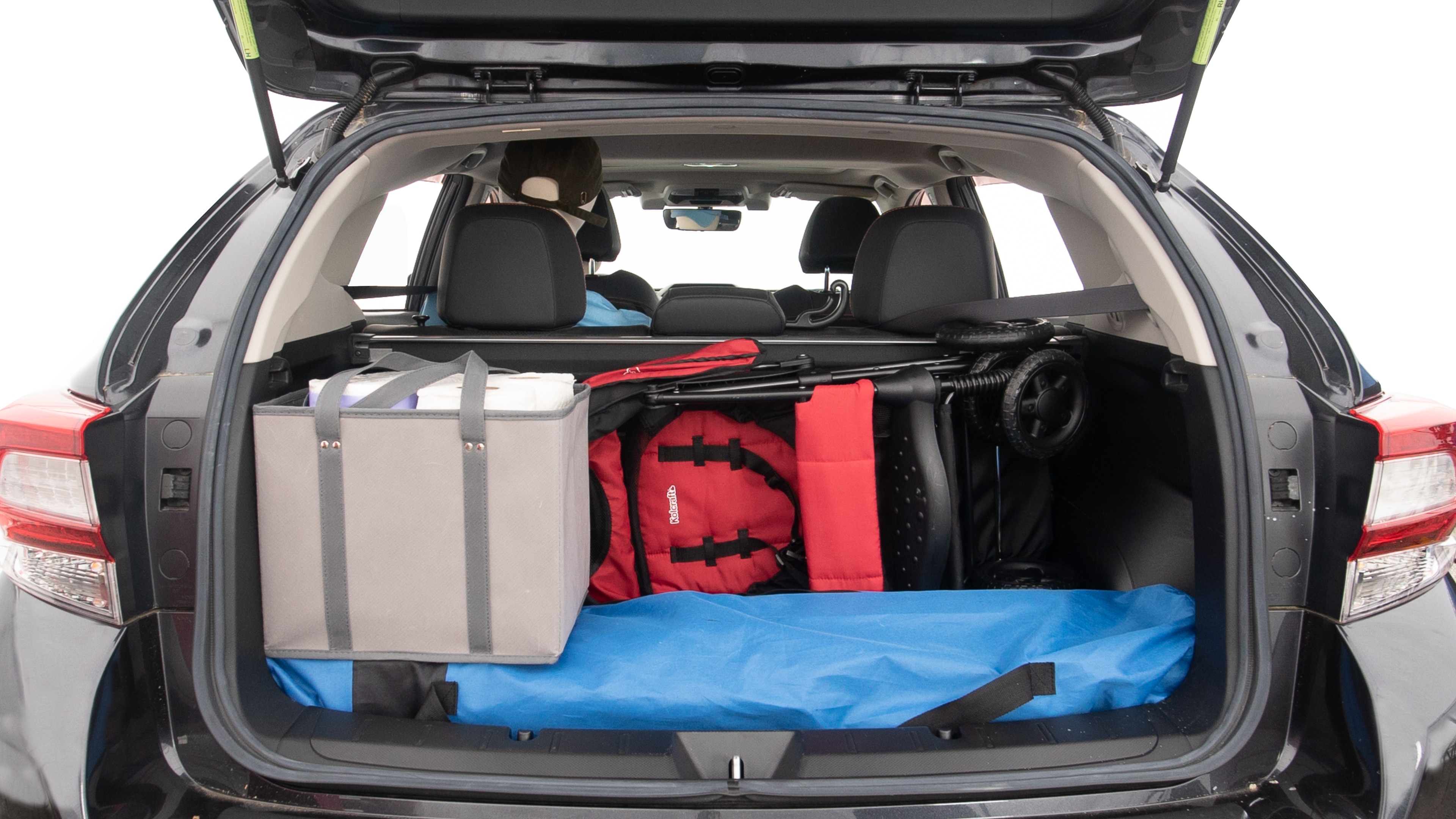 The trunk lid is open showing full view of the trunk. A baby stroller, three grocery carriers, two camping chairs in the carrying bag, and a set of golf clubs are placed inside.