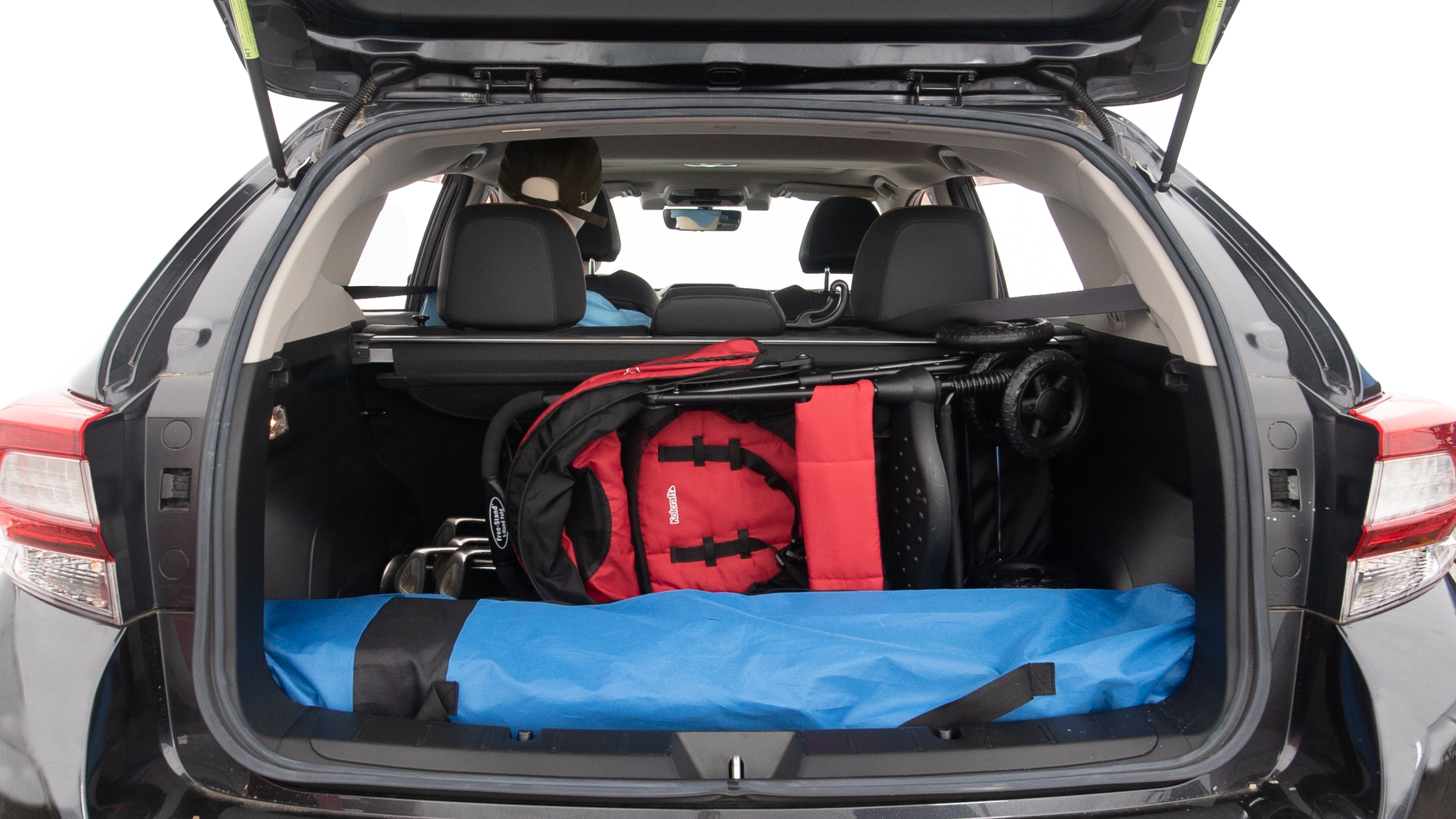 The trunk lid is open showing full view of the trunk. A baby stroller, three grocery carriers, two camping chairs in the carrying bag, and a set of golf clubs are placed inside.