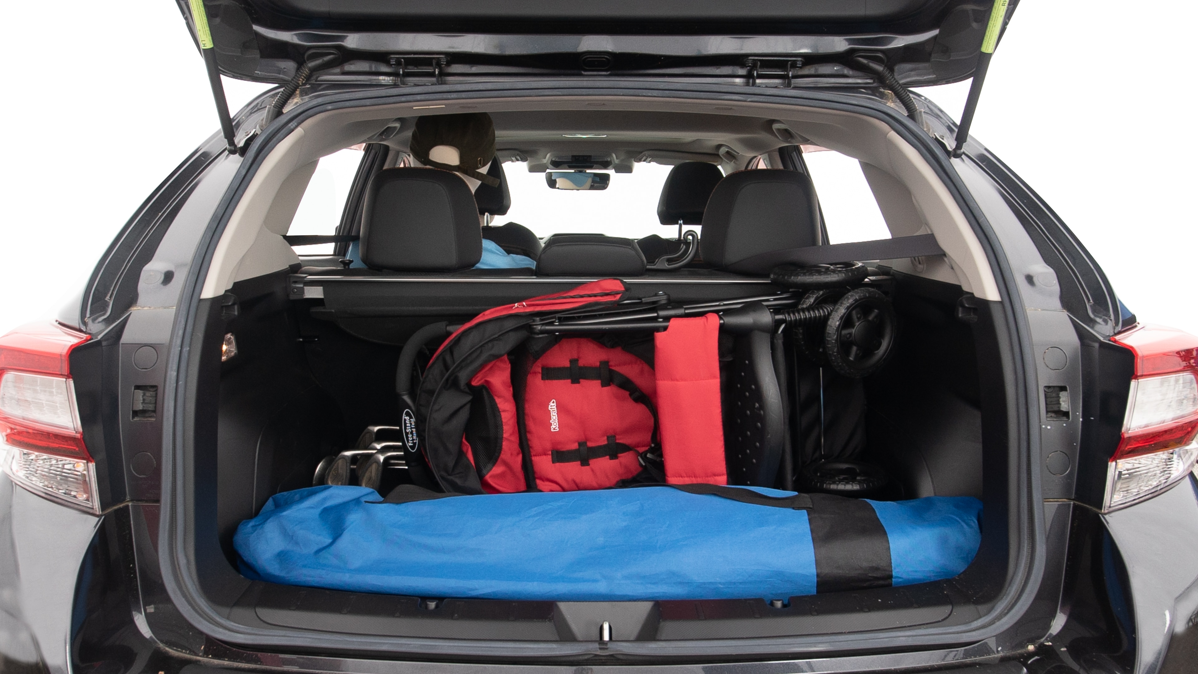 The trunk lid is open showing full view of the trunk. A baby stroller, three grocery carriers, two camping chairs in the carrying bag, and a set of golf clubs are placed inside.