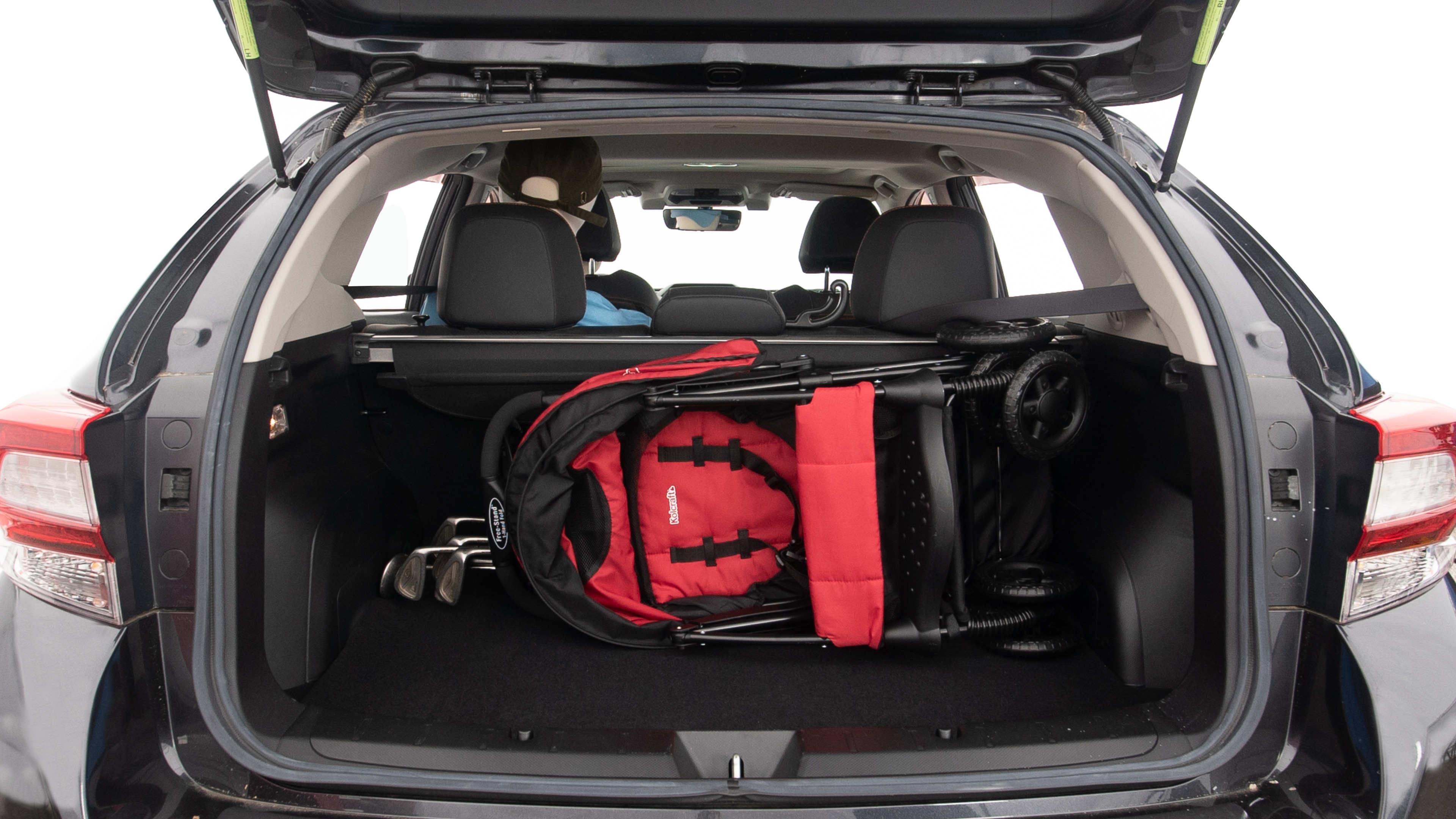 The trunk lid is open showing full view of the trunk. A baby stroller, three grocery carriers, two camping chairs in the carrying bag, and a set of golf clubs are placed inside.