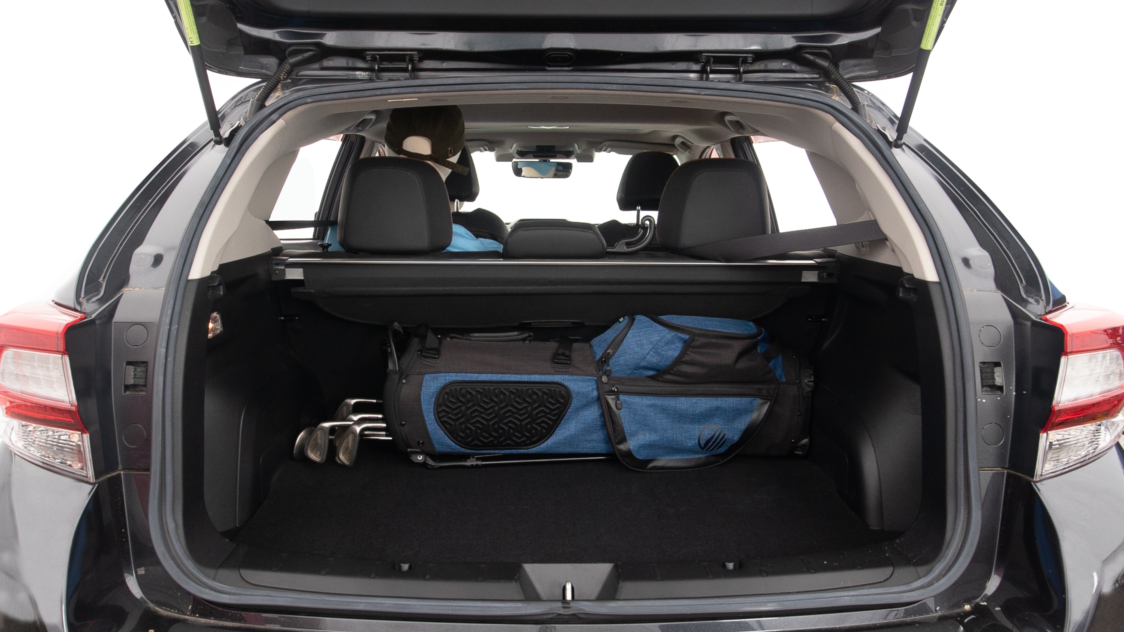 The trunk lid is open showing full view of the trunk. A baby stroller, three grocery carriers, two camping chairs in the carrying bag, and a set of golf clubs are placed inside.