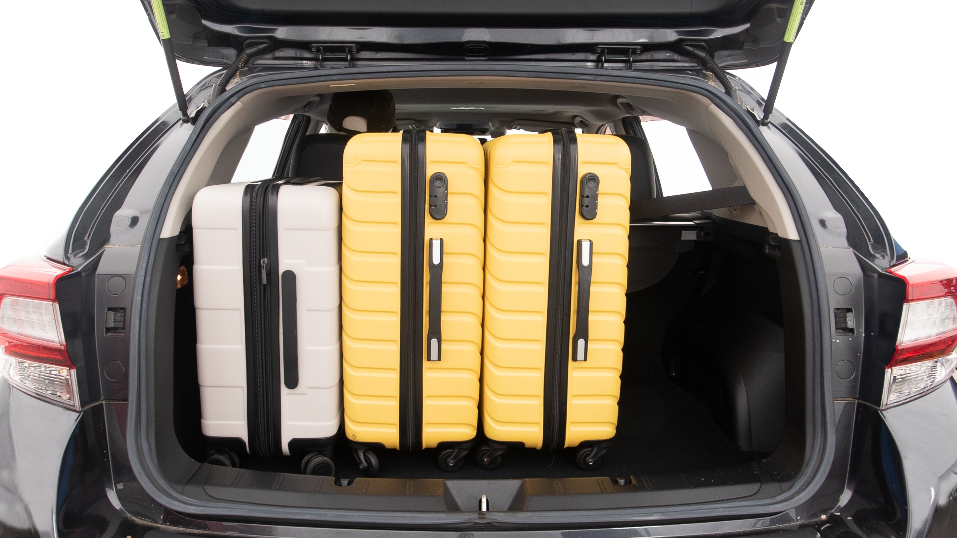 The trunk lid is open, showing full view of the trunk space. Two large and one small suitcases are placed inside.