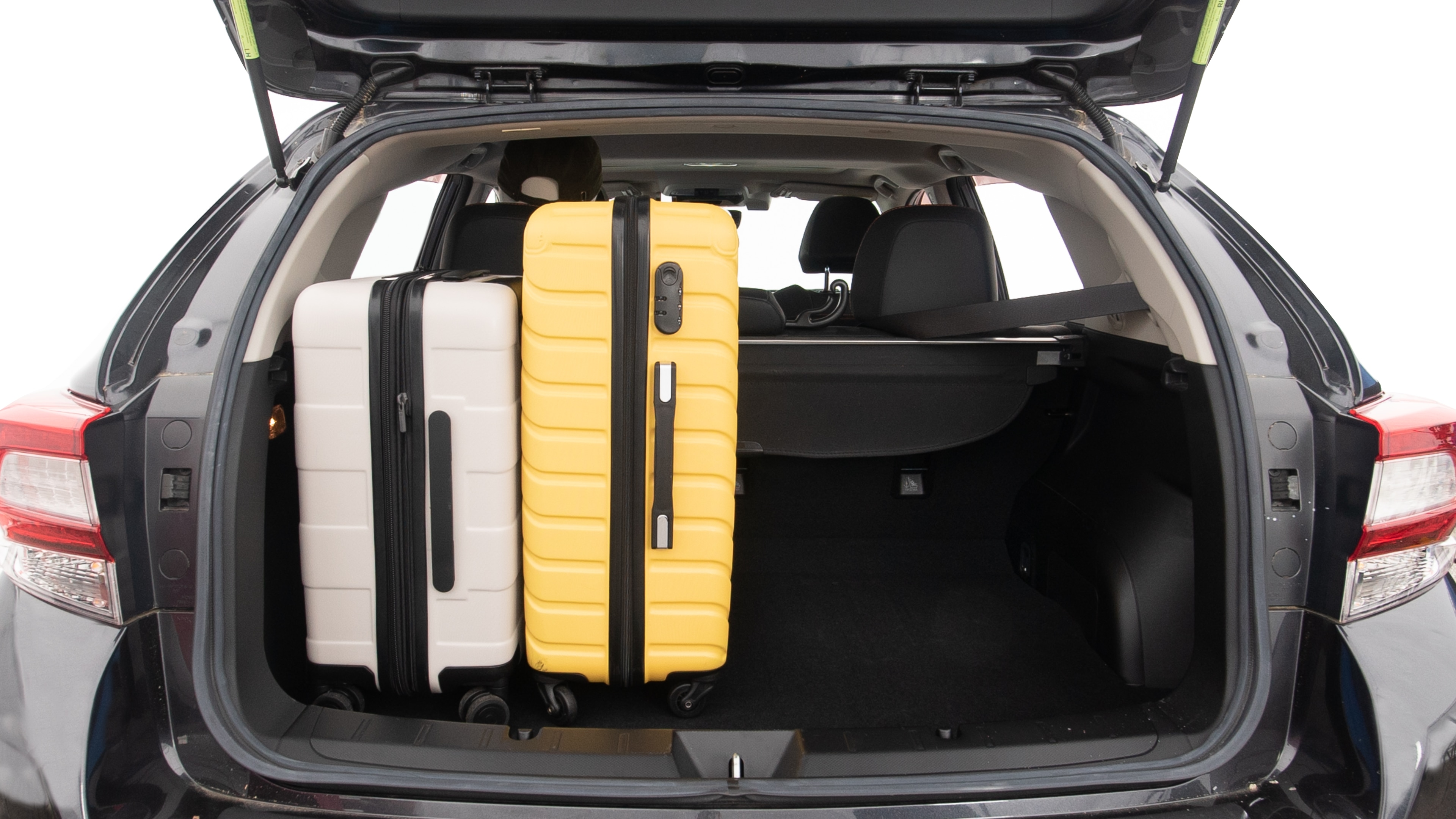 The trunk lid is open, showing full view of the trunk space. Two large and one small suitcases are placed inside.
