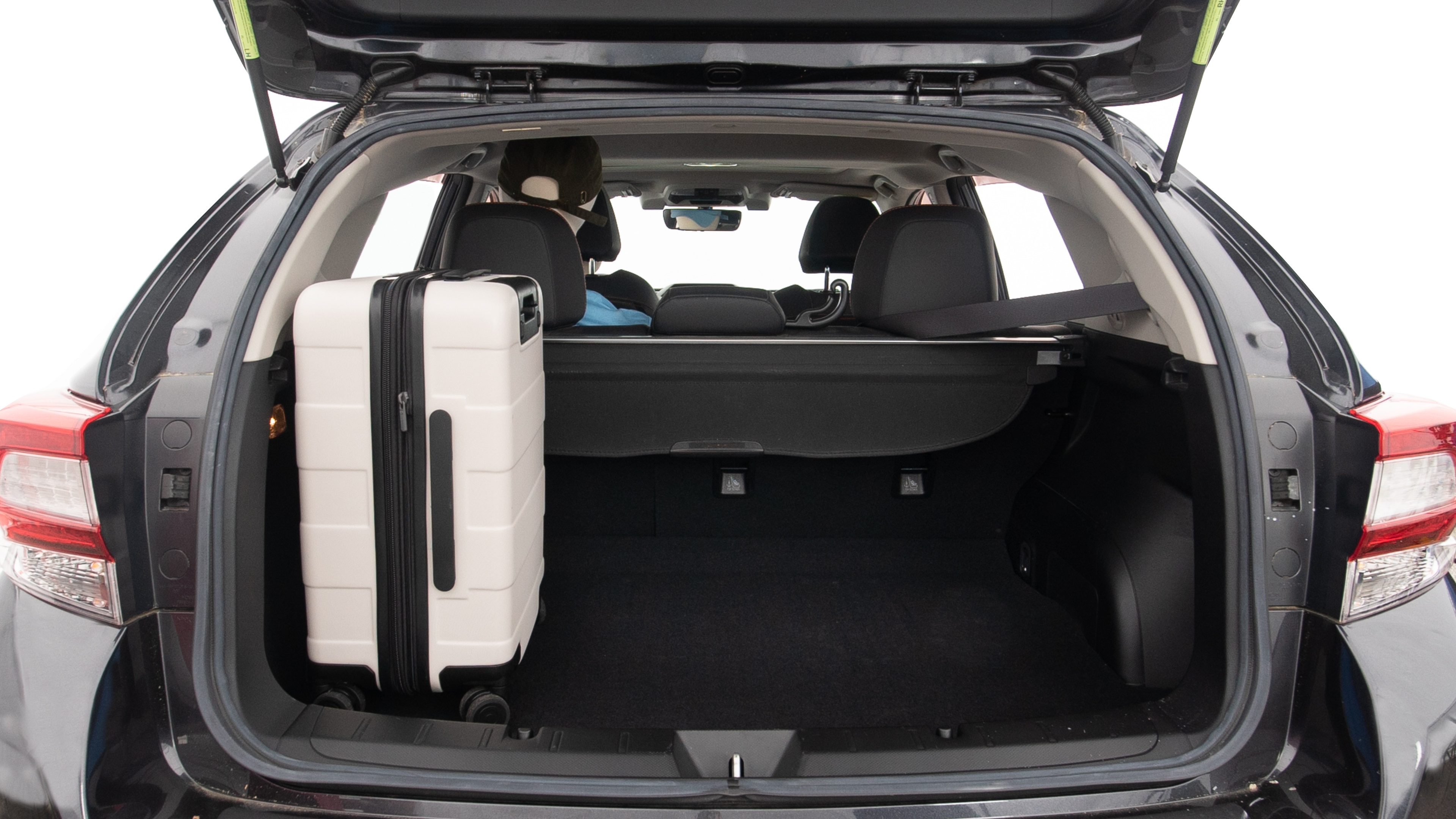 The trunk lid is open, showing full view of the trunk space. Two large and one small suitcases are placed inside.
