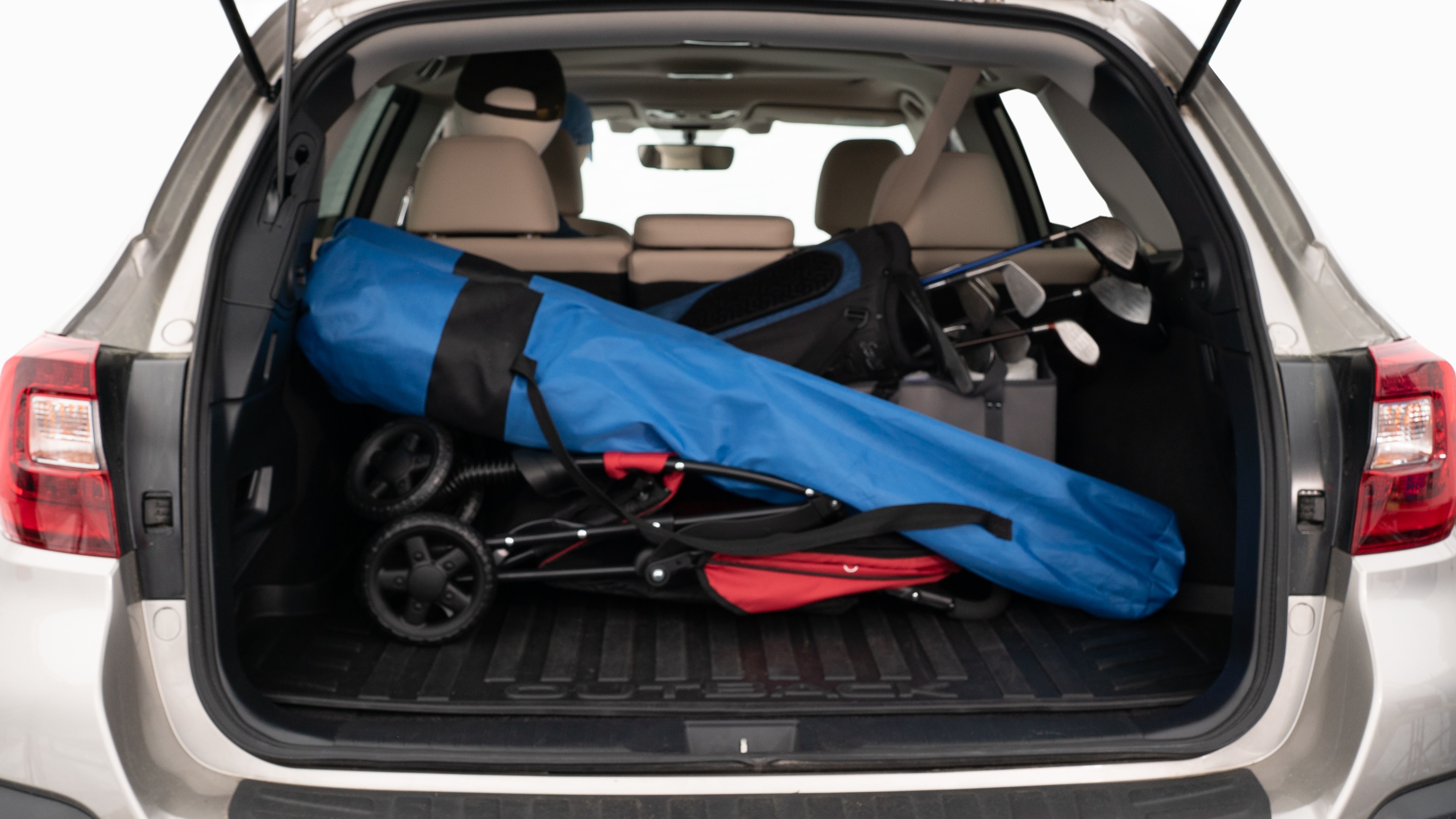 The trunk lid is open showing full view of the trunk. A baby stroller, three grocery carriers, two camping chairs in the carrying bag, and a set of golf clubs are placed inside.
