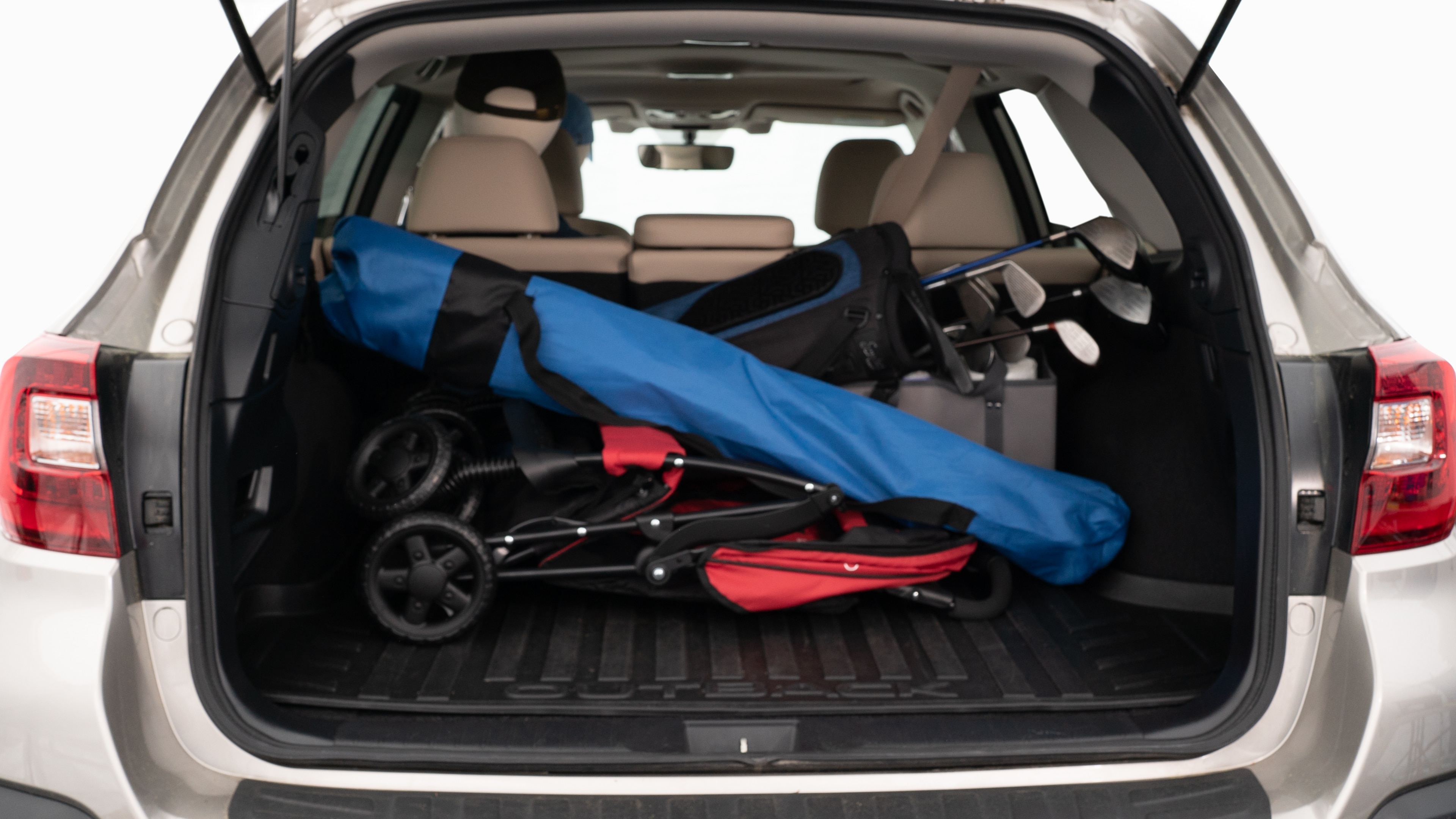 The trunk lid is open showing full view of the trunk. A baby stroller, three grocery carriers, two camping chairs in the carrying bag, and a set of golf clubs are placed inside.