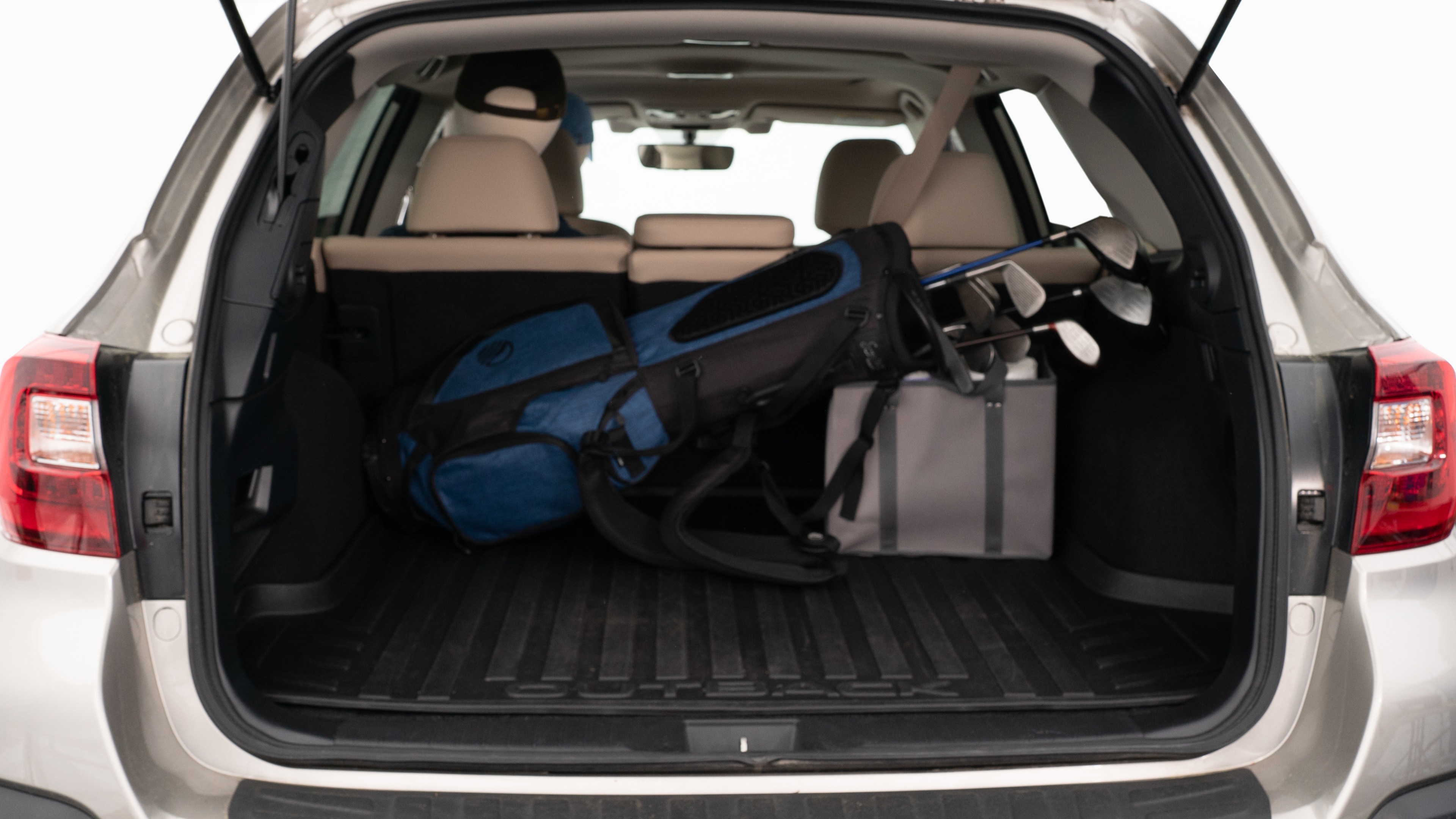 The trunk lid is open showing full view of the trunk. A baby stroller, three grocery carriers, two camping chairs in the carrying bag, and a set of golf clubs are placed inside.