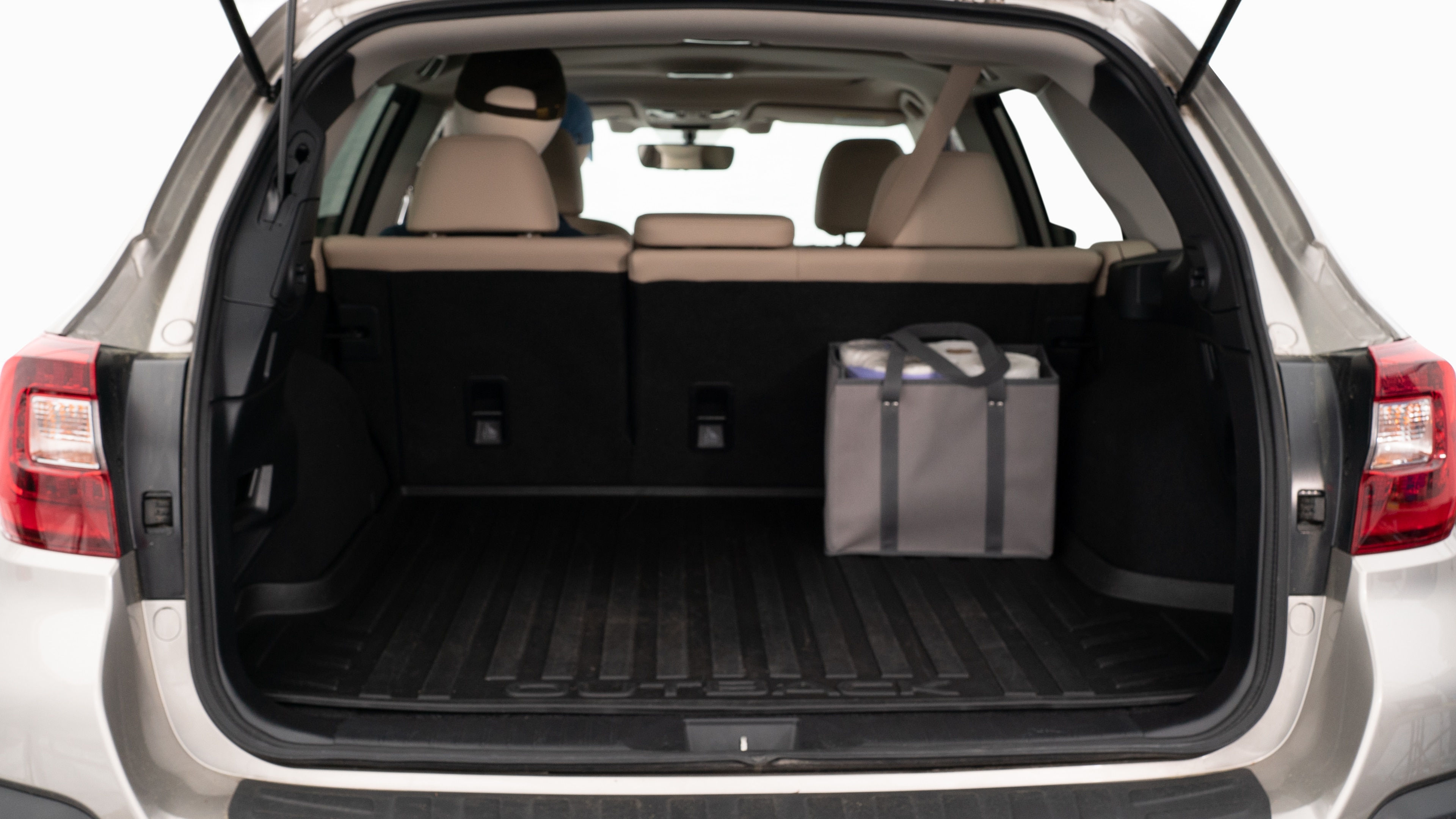 The trunk lid is open showing full view of the trunk. A baby stroller, three grocery carriers, two camping chairs in the carrying bag, and a set of golf clubs are placed inside.